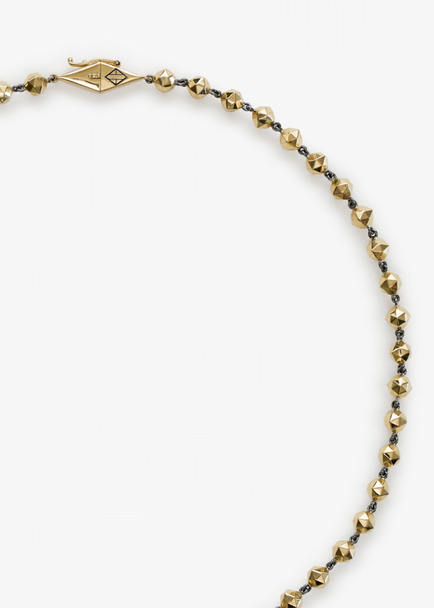 Person wearing a black shirt with a necklace against a neutral background.