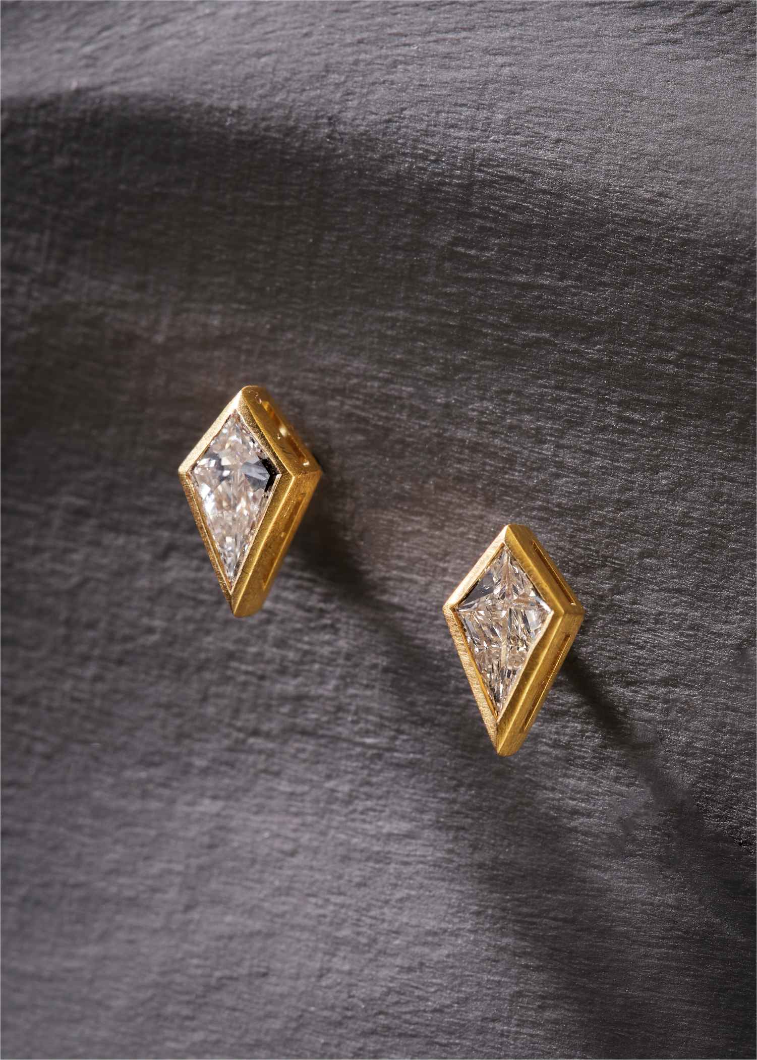 Diamond-shaped earrings with gold frames on a white background.
