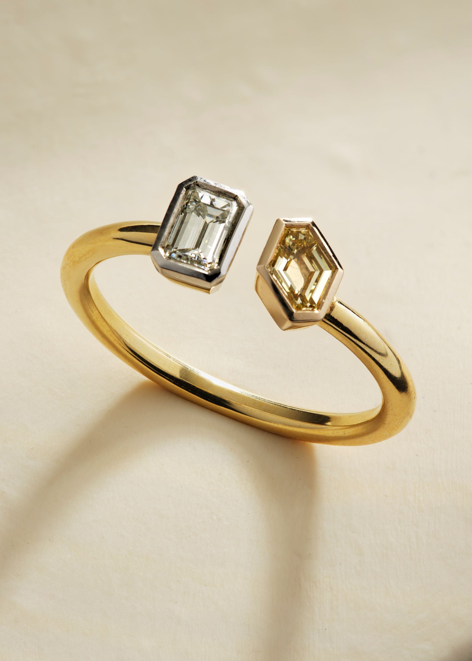 Yellow gold toi et moi ring showcasing twin emerald-cut diamonds in white and champagne tones.