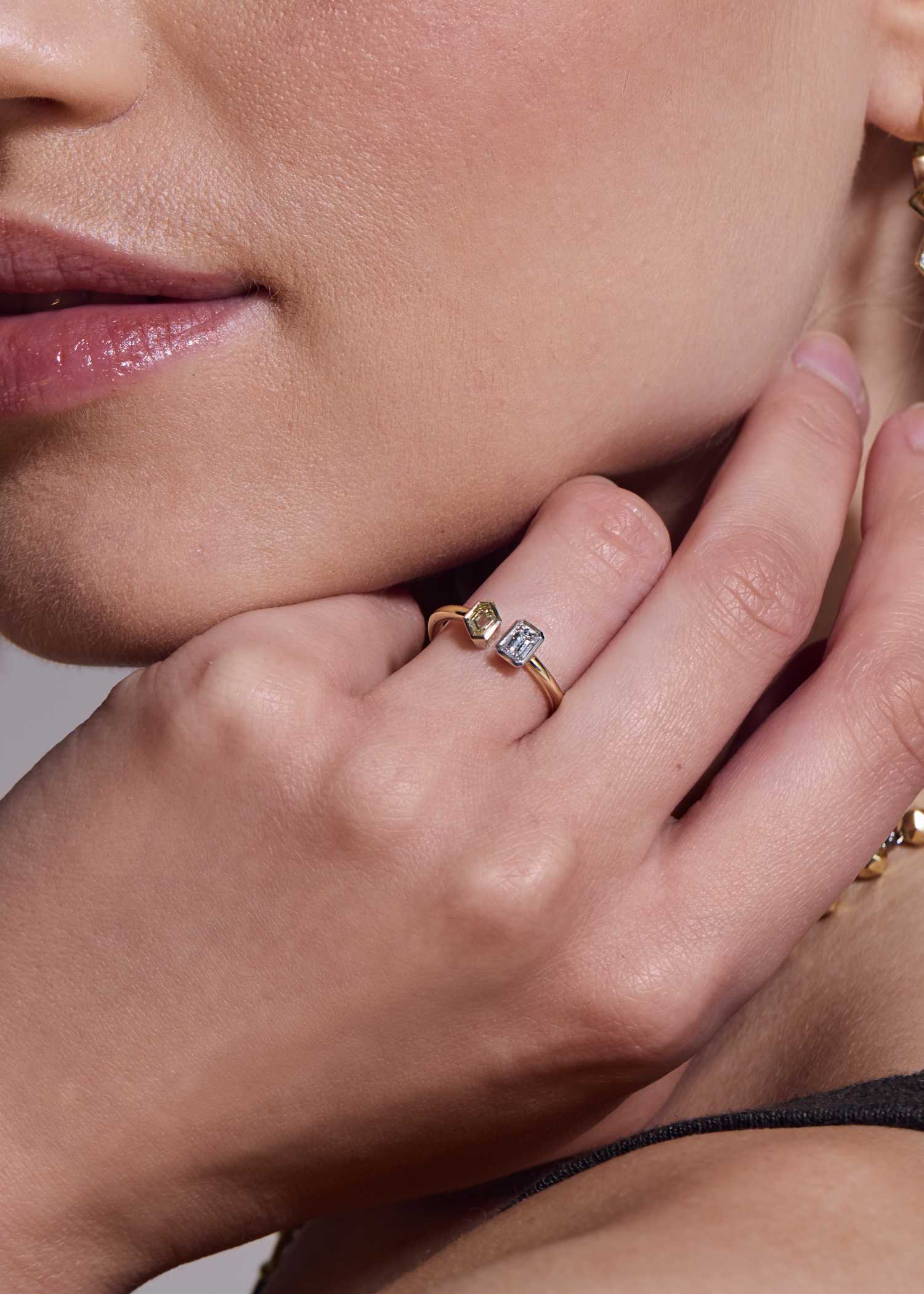 Close-up of toi et moi ring featuring white and champagne emerald-cut diamonds set in yellow gold.