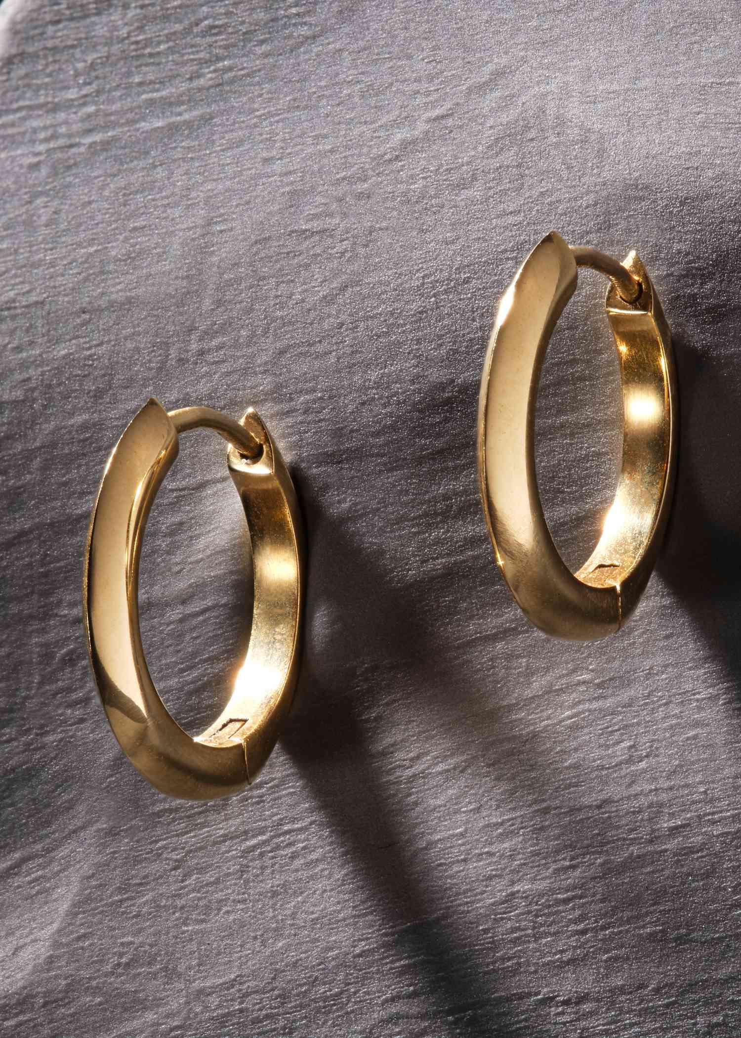 Gold stain hoop earrings on a white background.