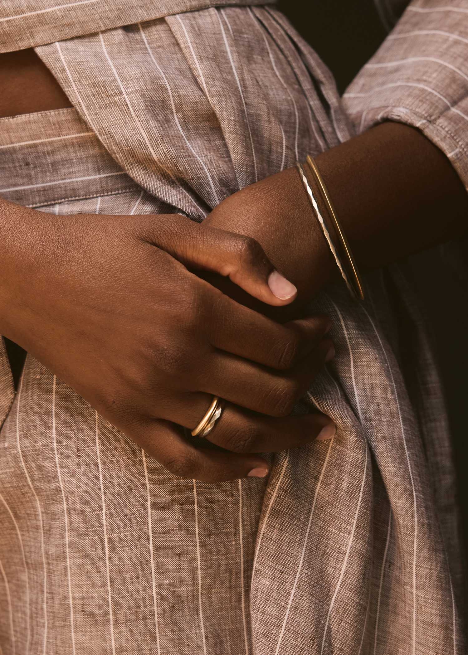 Close-up of a person wearing a brown garment with a belt and cuff detail.