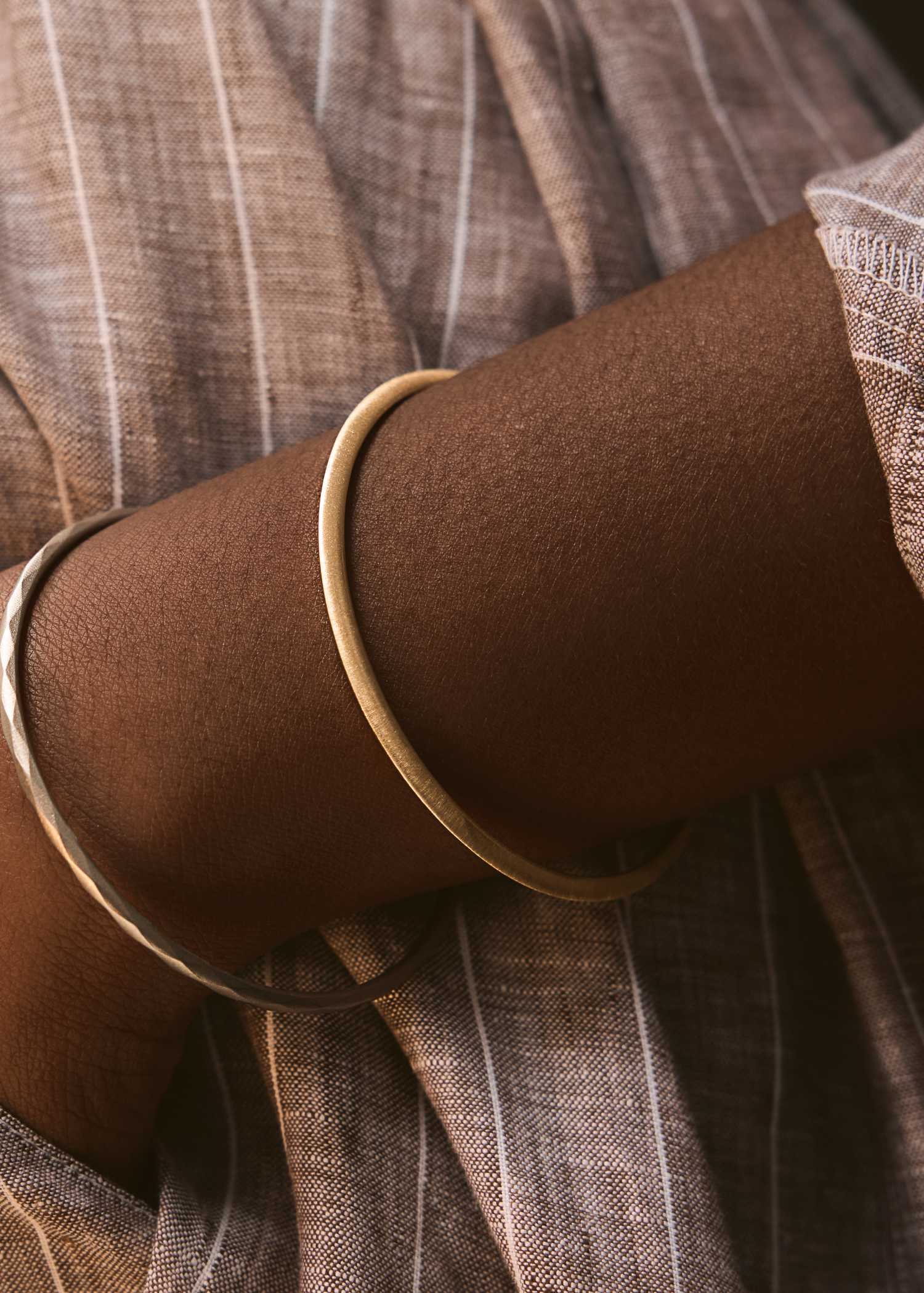 Yellow gold bracelet on a textured gray surface.