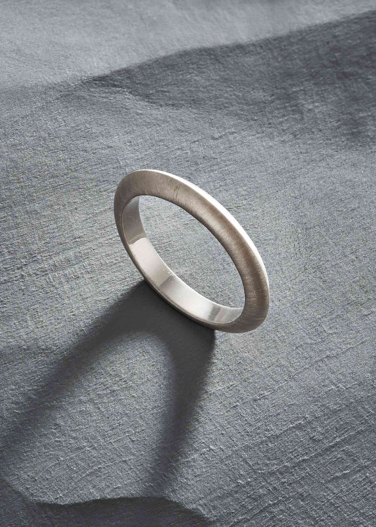 Close-up of a person wearing a brown pinstripe garment with a gold ring and bracelet.