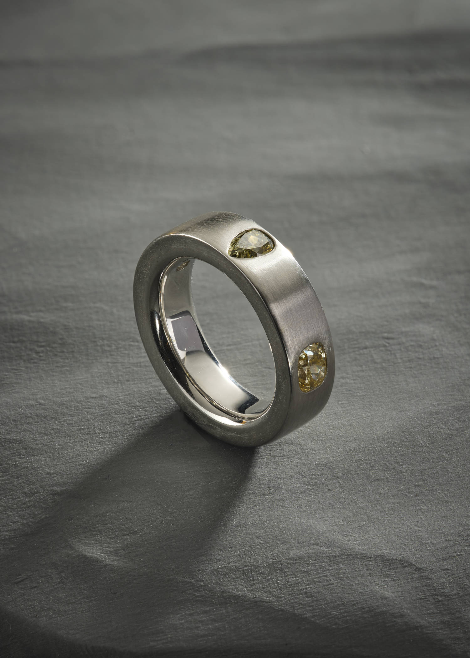 Platinum ring with pear-cut diamonds on matte textured surface.