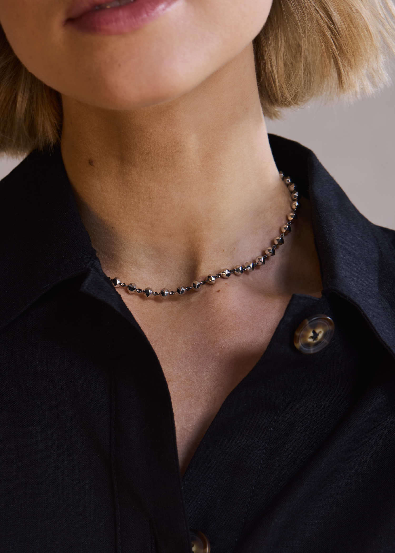 Model wearing white gold facet bead necklace.