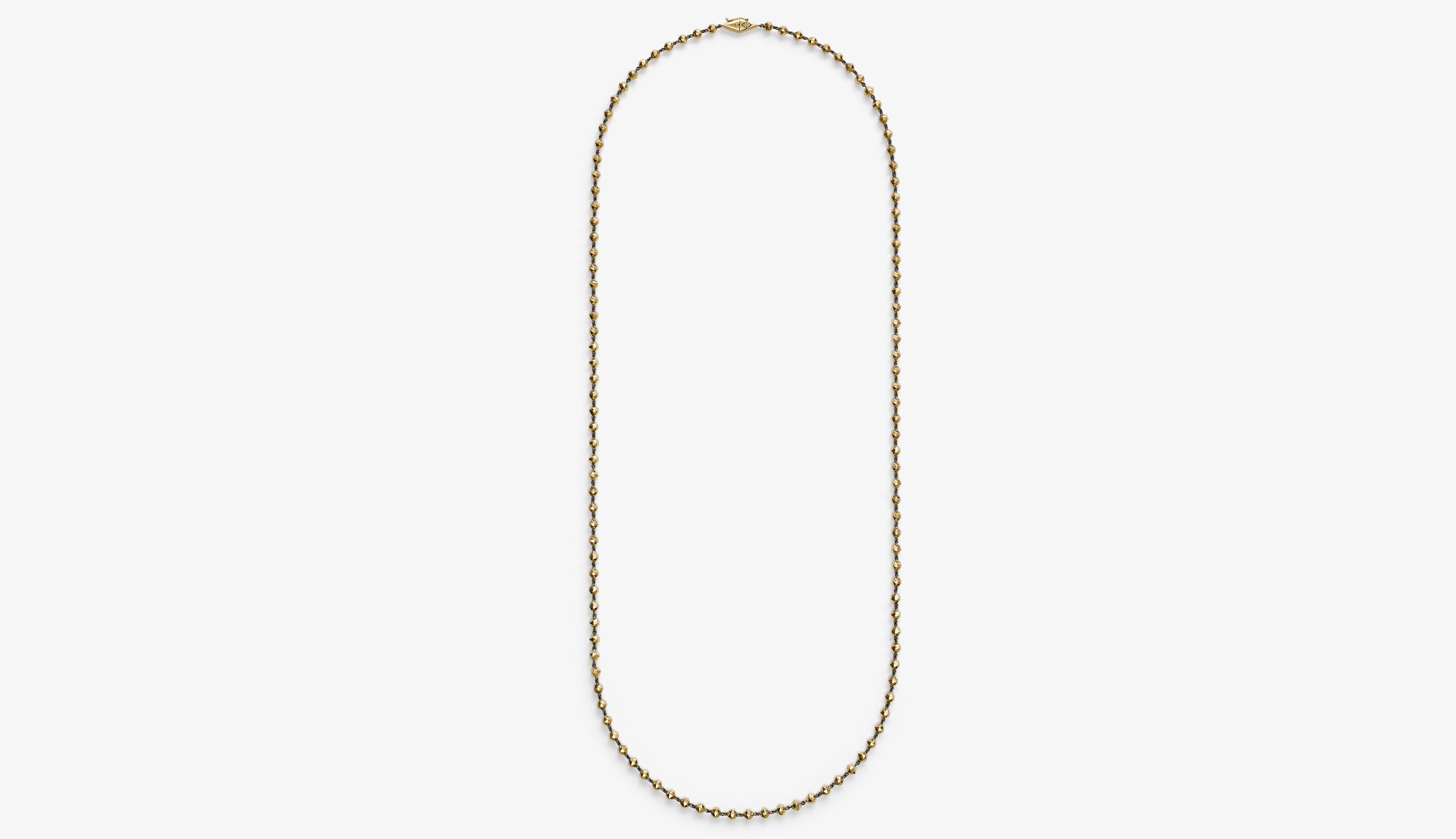 Blonde woman with slicked-back hair wearing a black strapless top and a choker necklace with a large light blue gemstone.