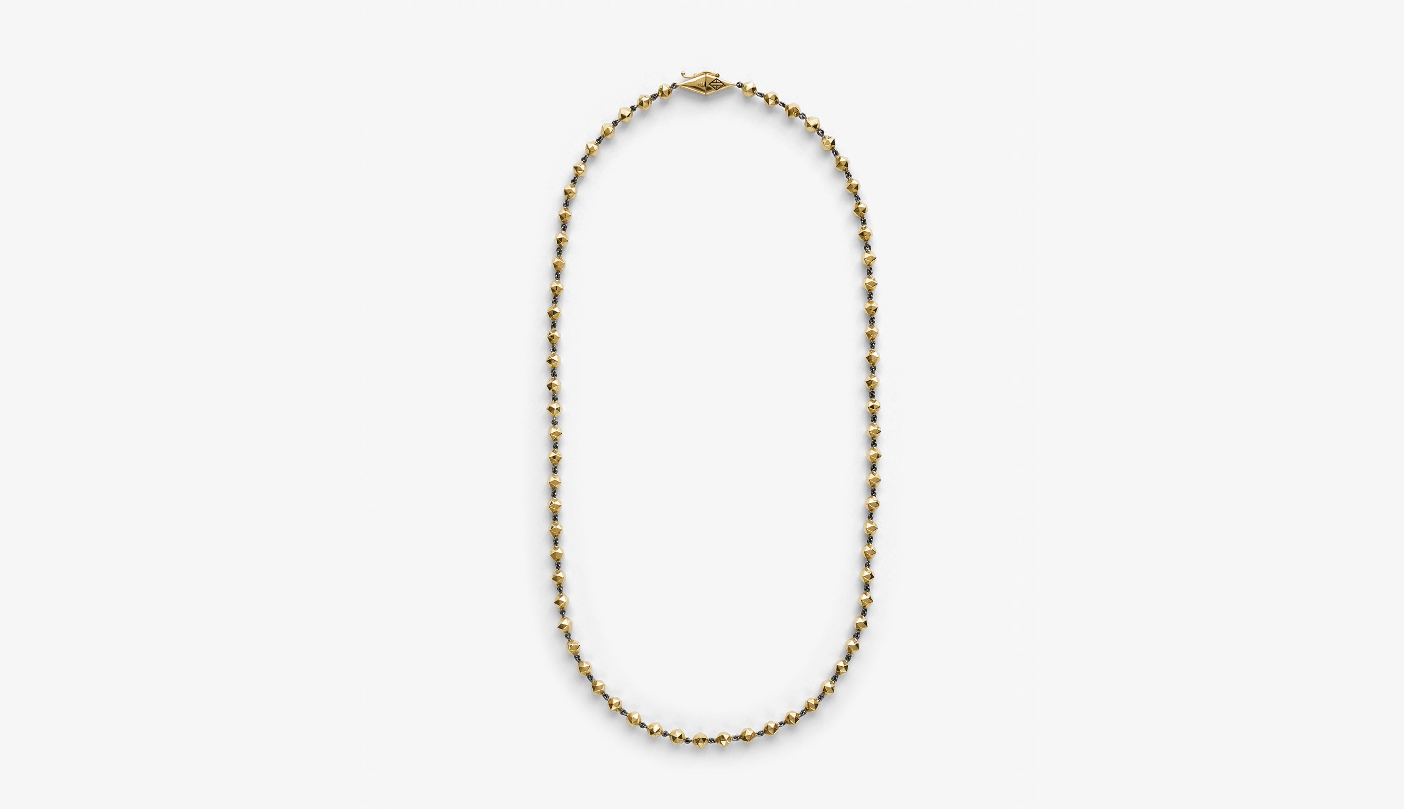 Blonde woman with slicked-back hair wearing a black strapless top and a choker necklace with a large light blue gemstone.