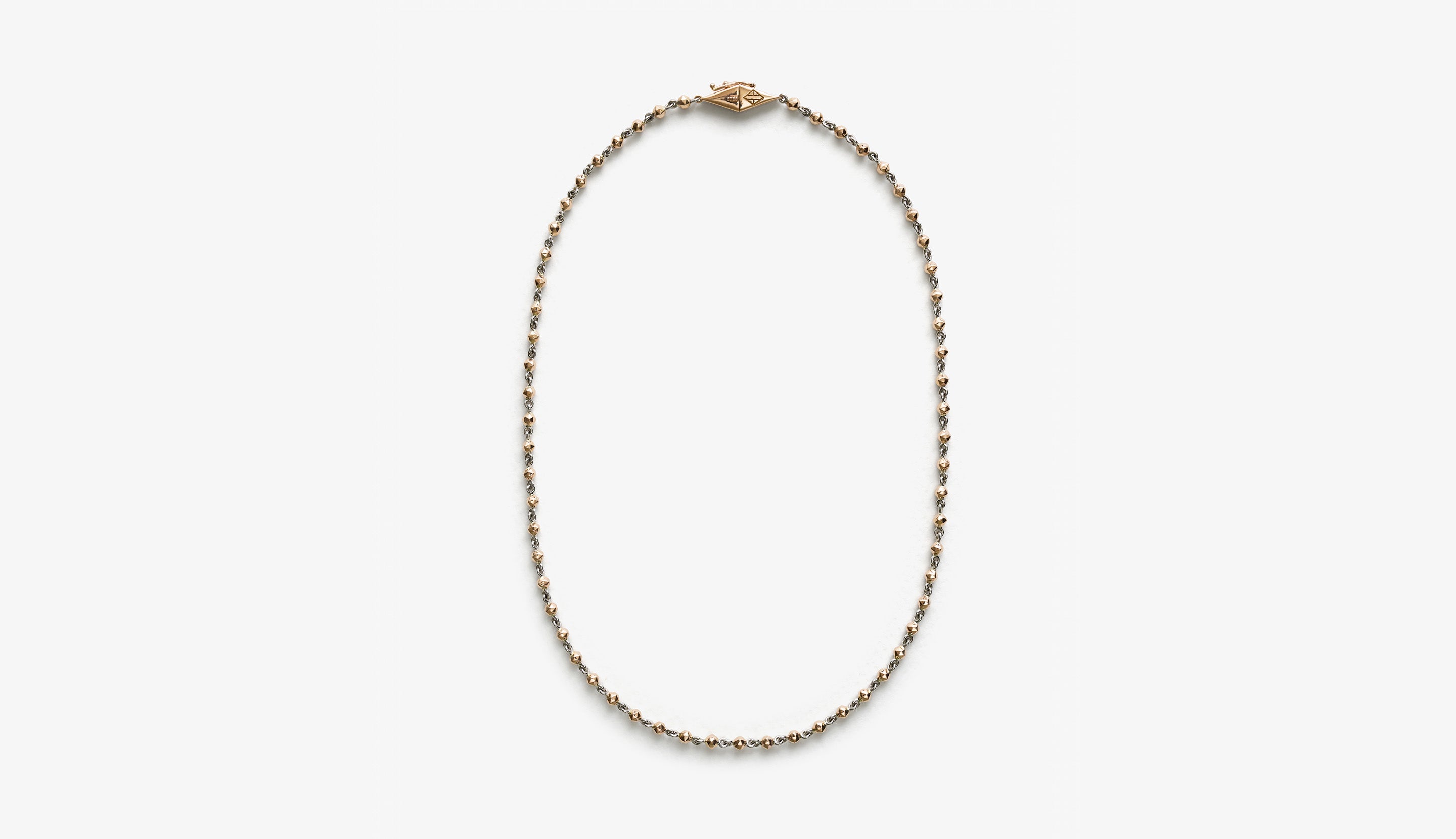 Blonde woman with slicked-back hair wearing a black strapless top and a choker necklace with a large light blue gemstone.