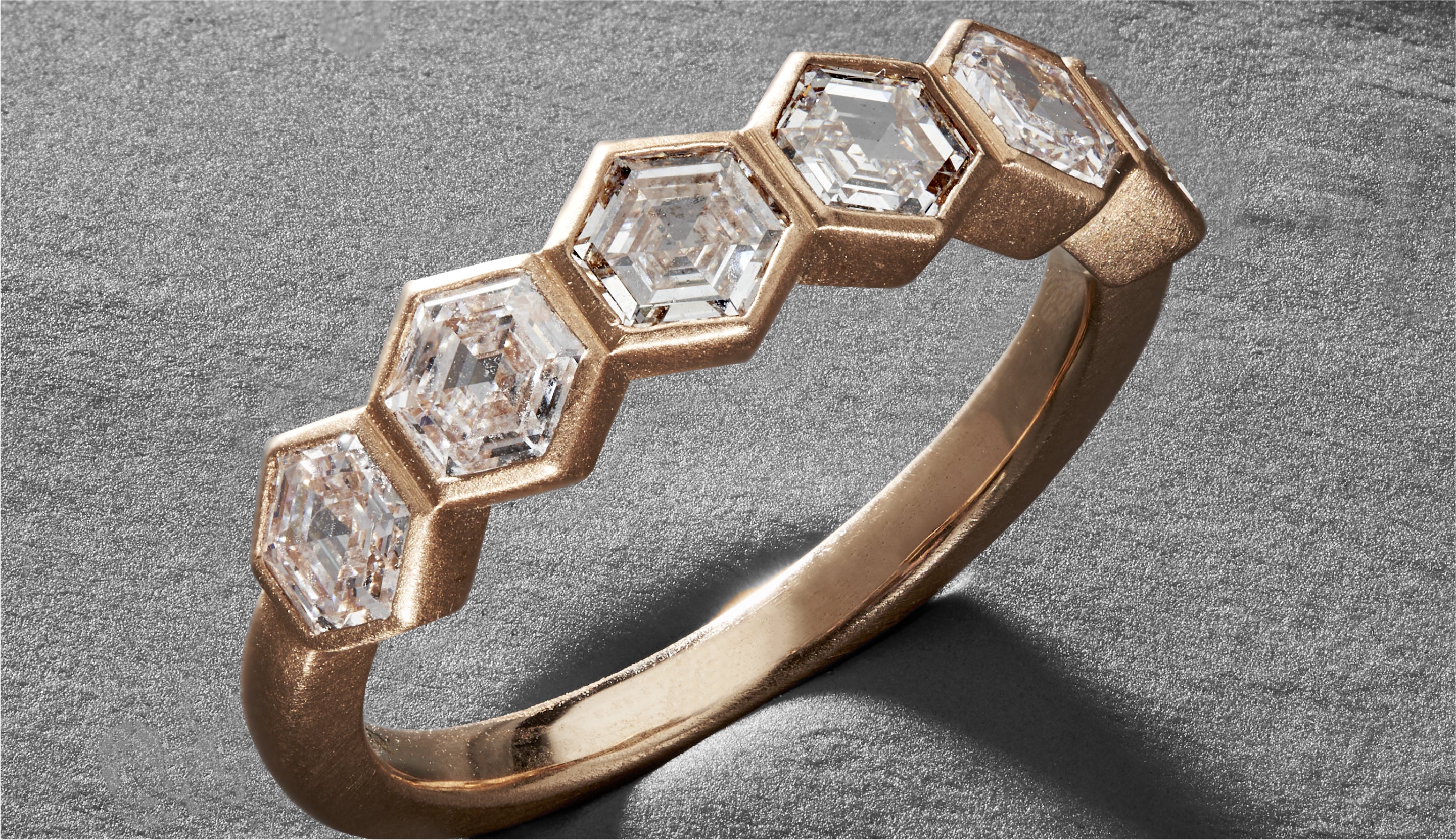 Blonde woman with slicked-back hair wearing a black strapless top and a choker necklace with a large light blue gemstone.