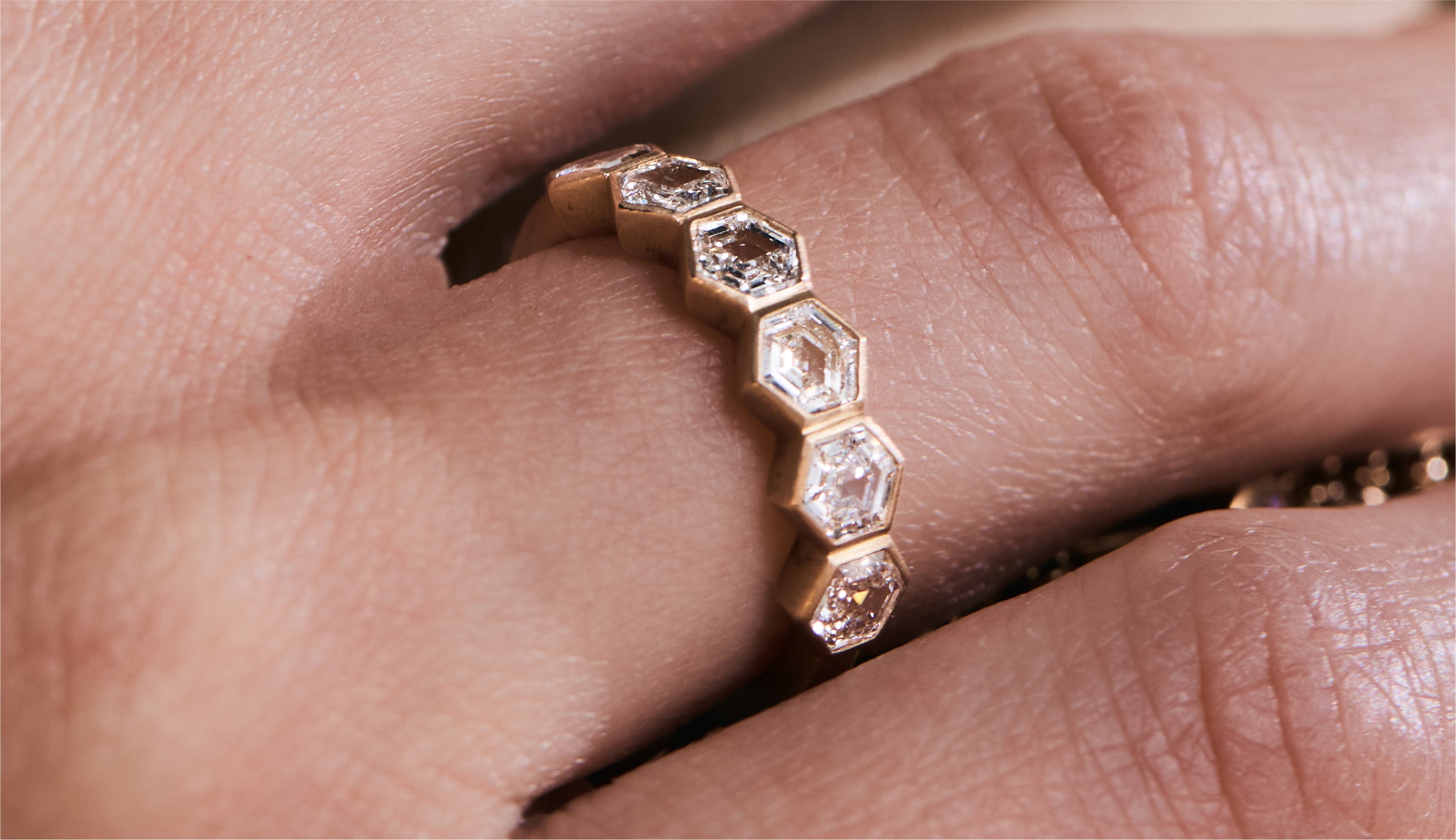 Blonde woman with slicked-back hair wearing a black strapless top and a choker necklace with a large light blue gemstone.