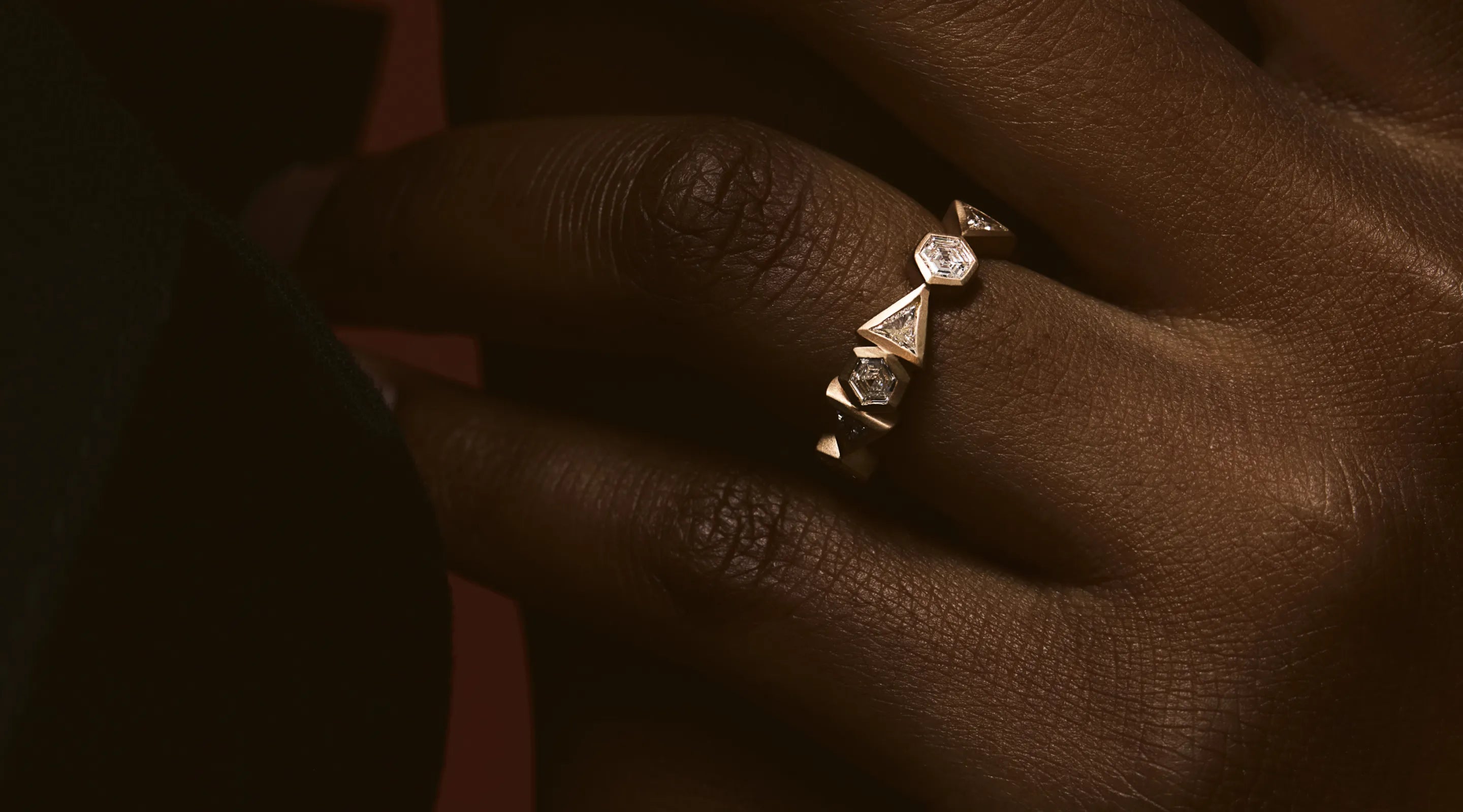 Blonde woman with slicked-back hair wearing a black strapless top and a choker necklace with a large light blue gemstone.