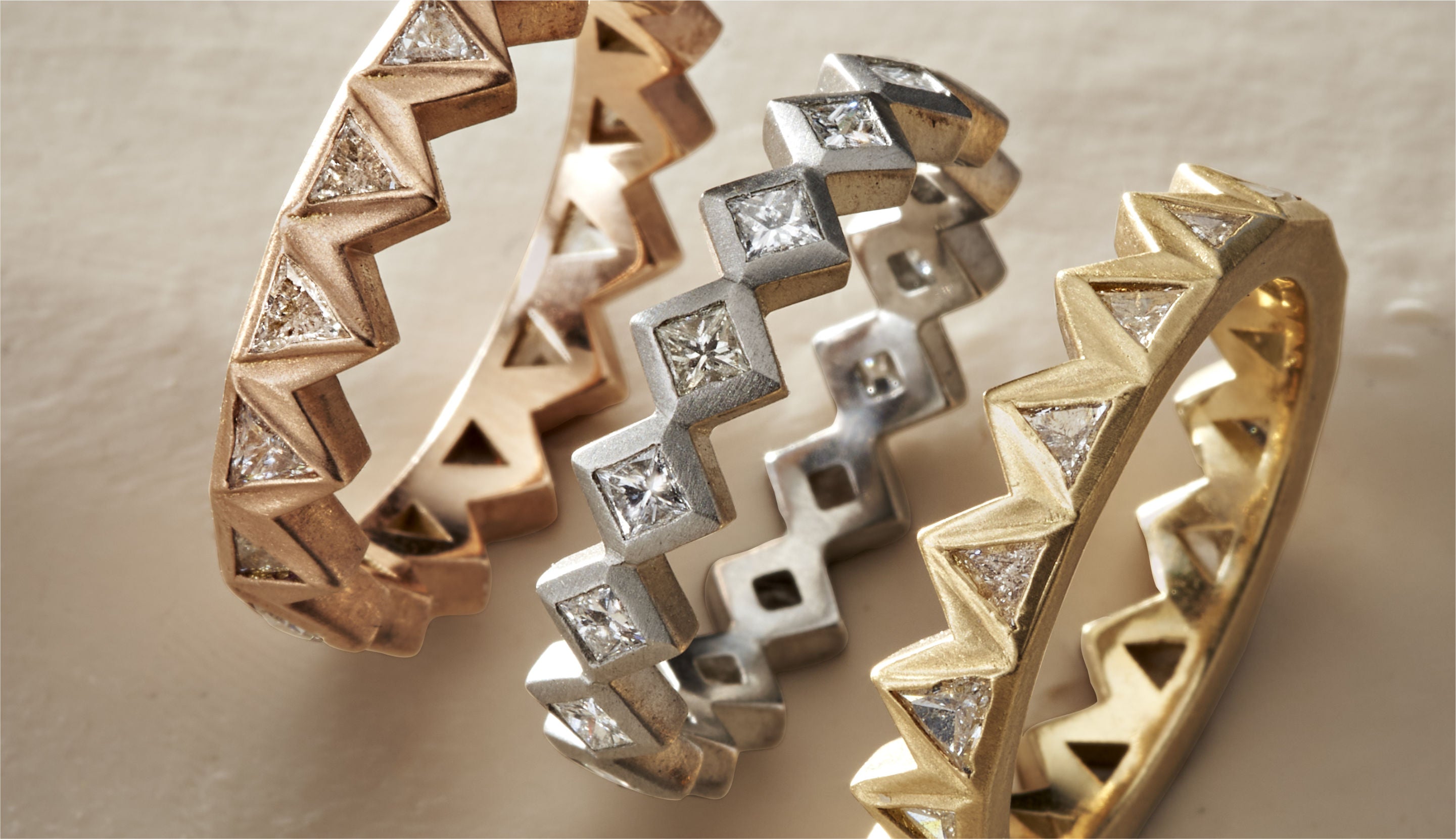 Blonde woman with slicked-back hair wearing a black strapless top and a choker necklace with a large light blue gemstone.