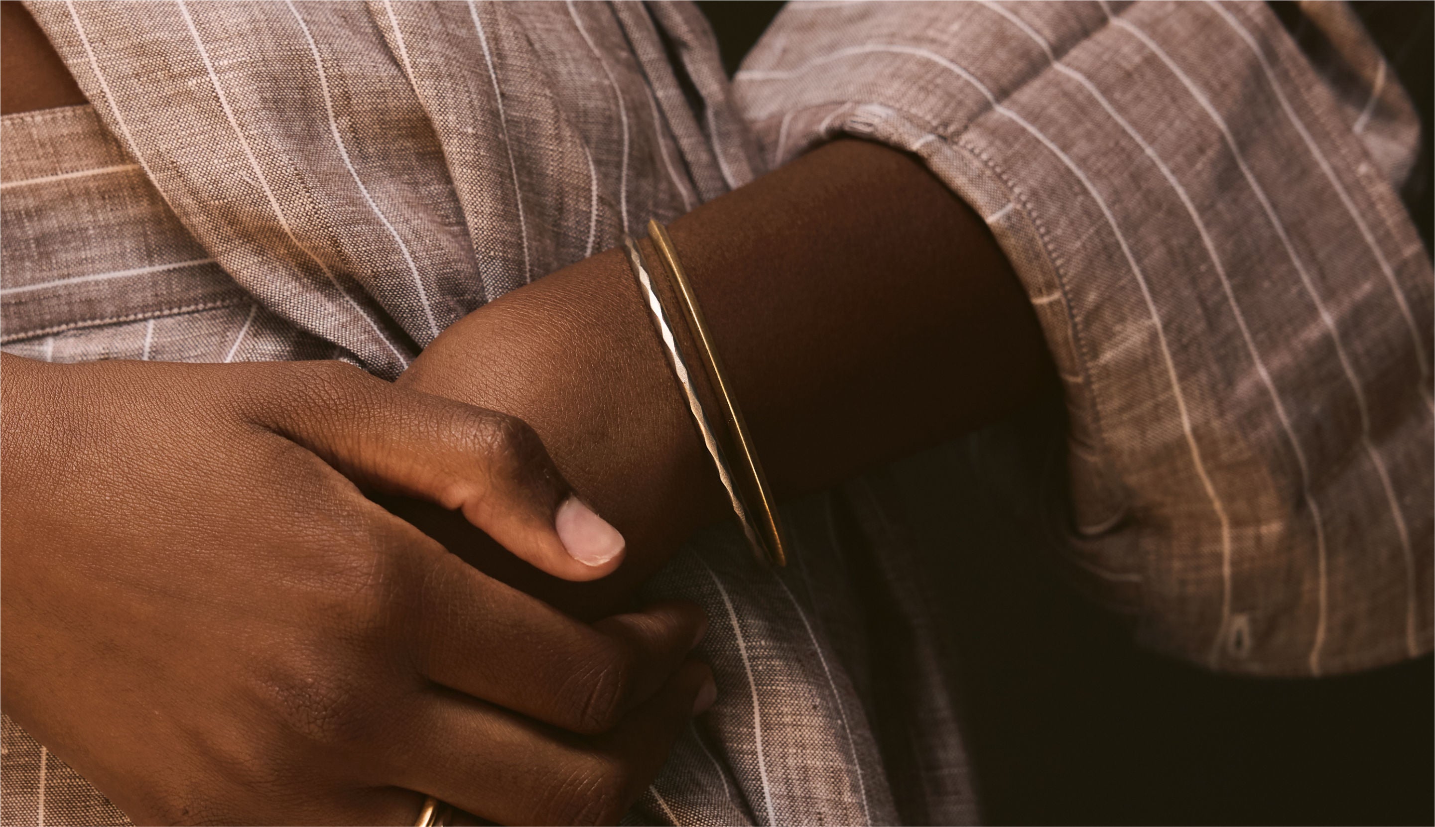 Blonde woman with slicked-back hair wearing a black strapless top and a choker necklace with a large light blue gemstone.