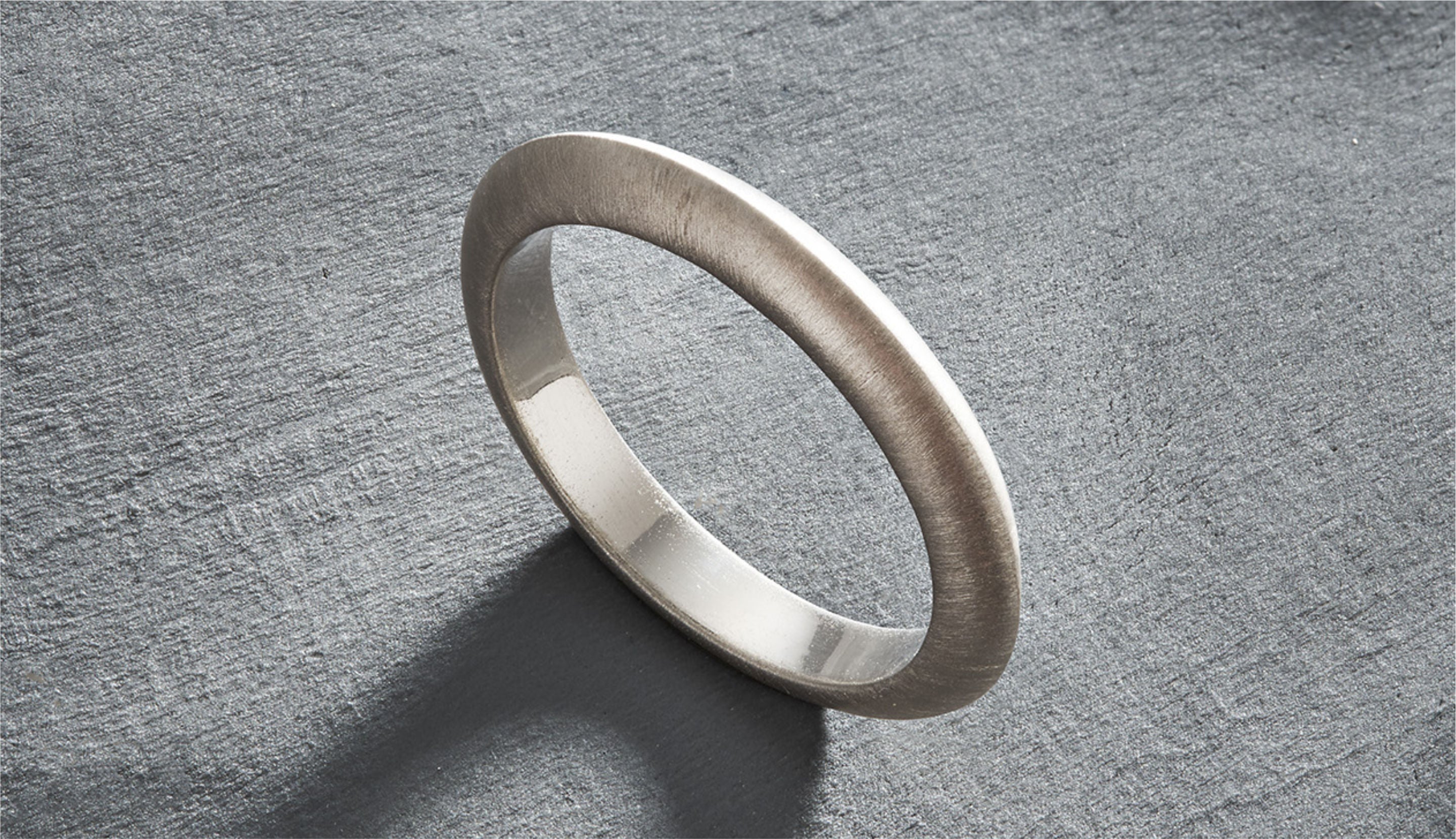 Blonde woman with slicked-back hair wearing a black strapless top and a choker necklace with a large light blue gemstone.