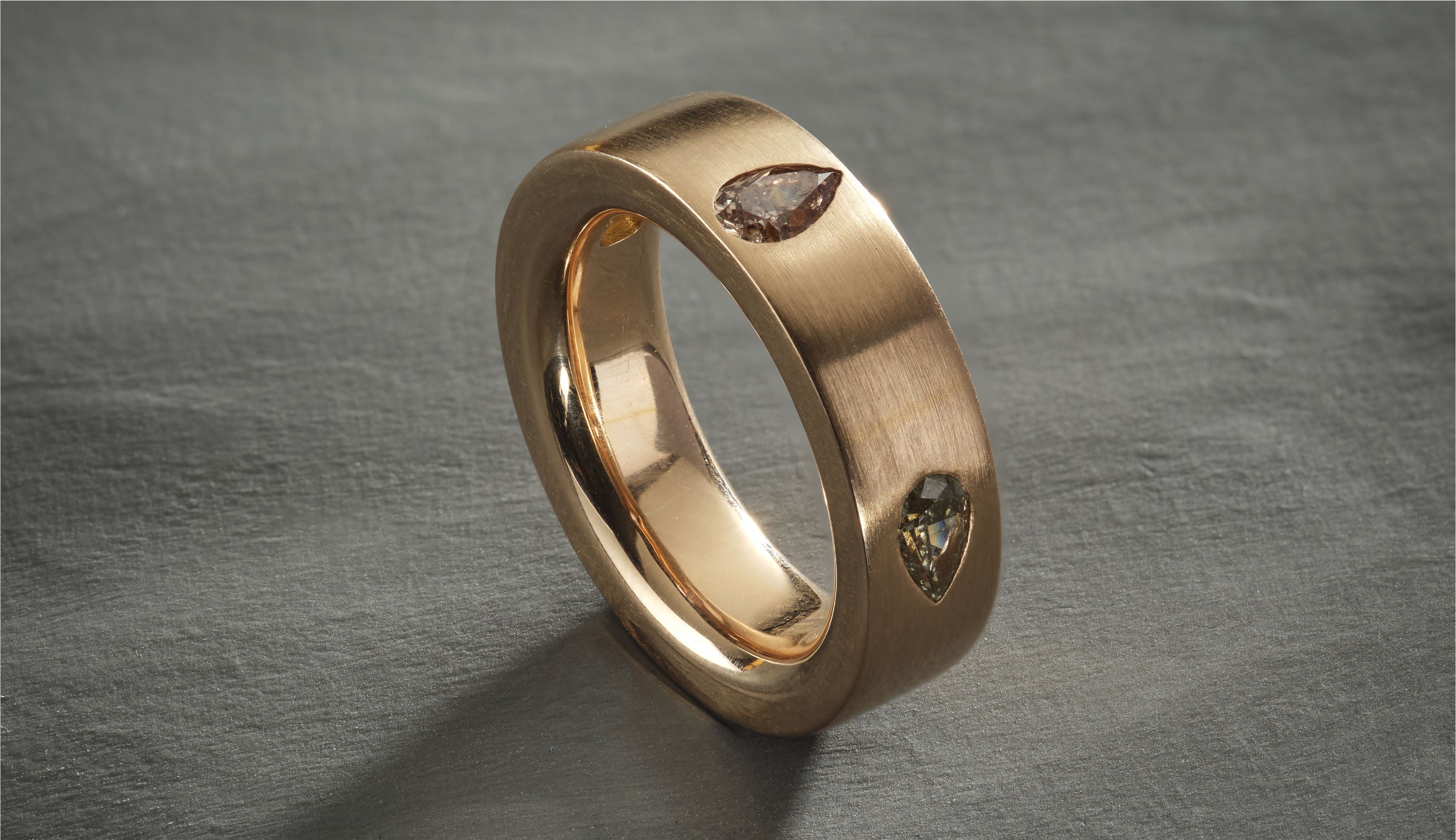 Blonde woman with slicked-back hair wearing a black strapless top and a choker necklace with a large light blue gemstone.