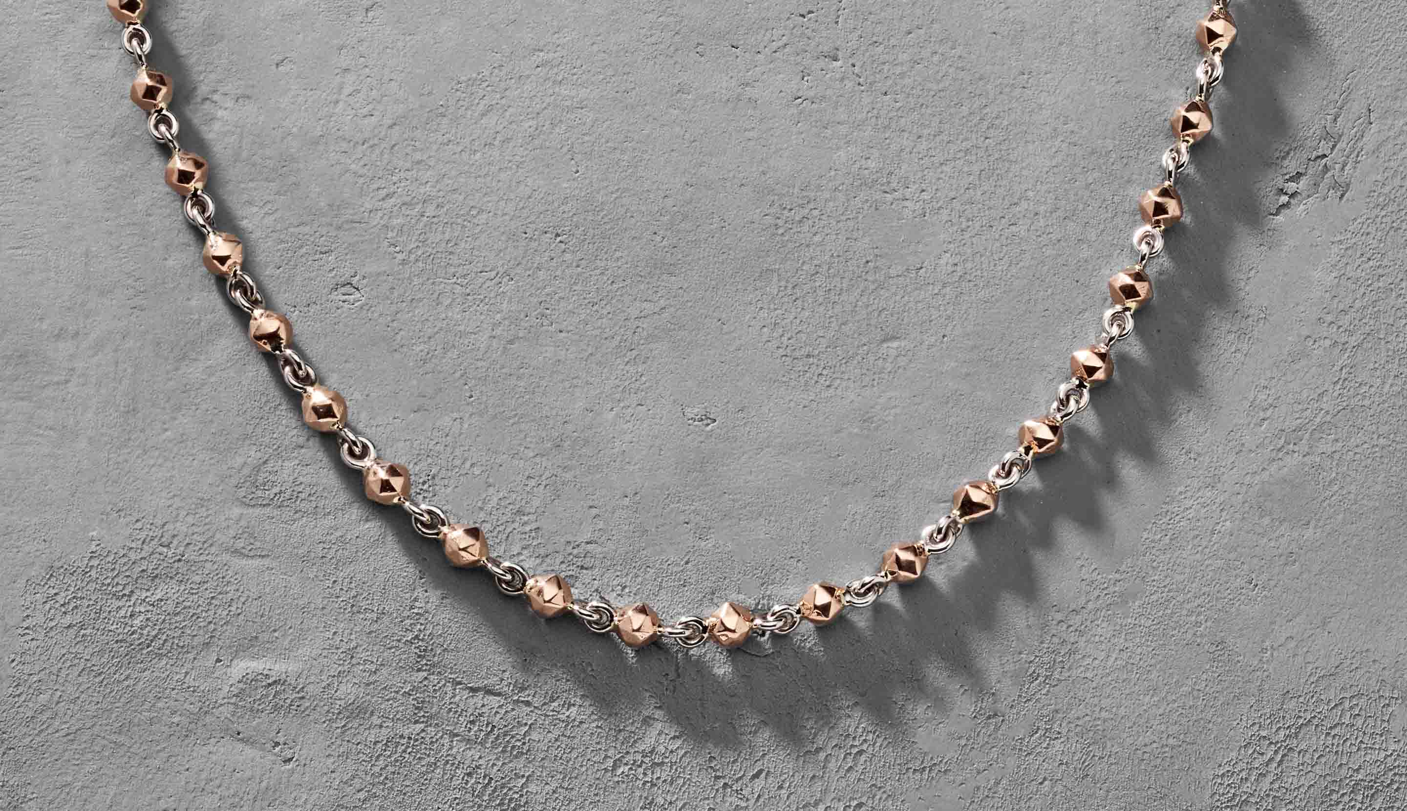 Blonde woman with slicked-back hair wearing a black strapless top and a choker necklace with a large light blue gemstone.