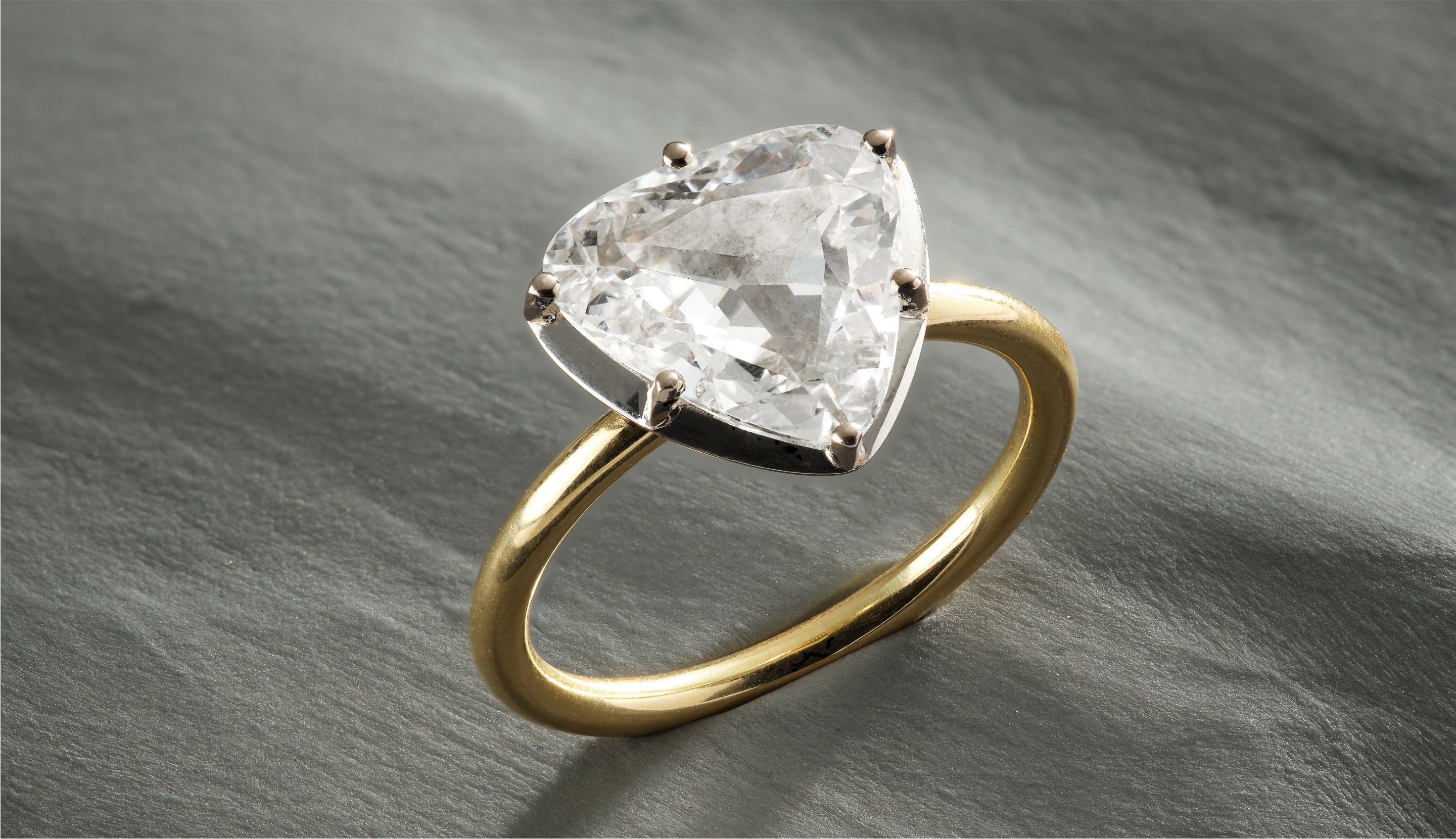 Blonde woman with slicked-back hair wearing a black strapless top and a choker necklace with a large light blue gemstone.