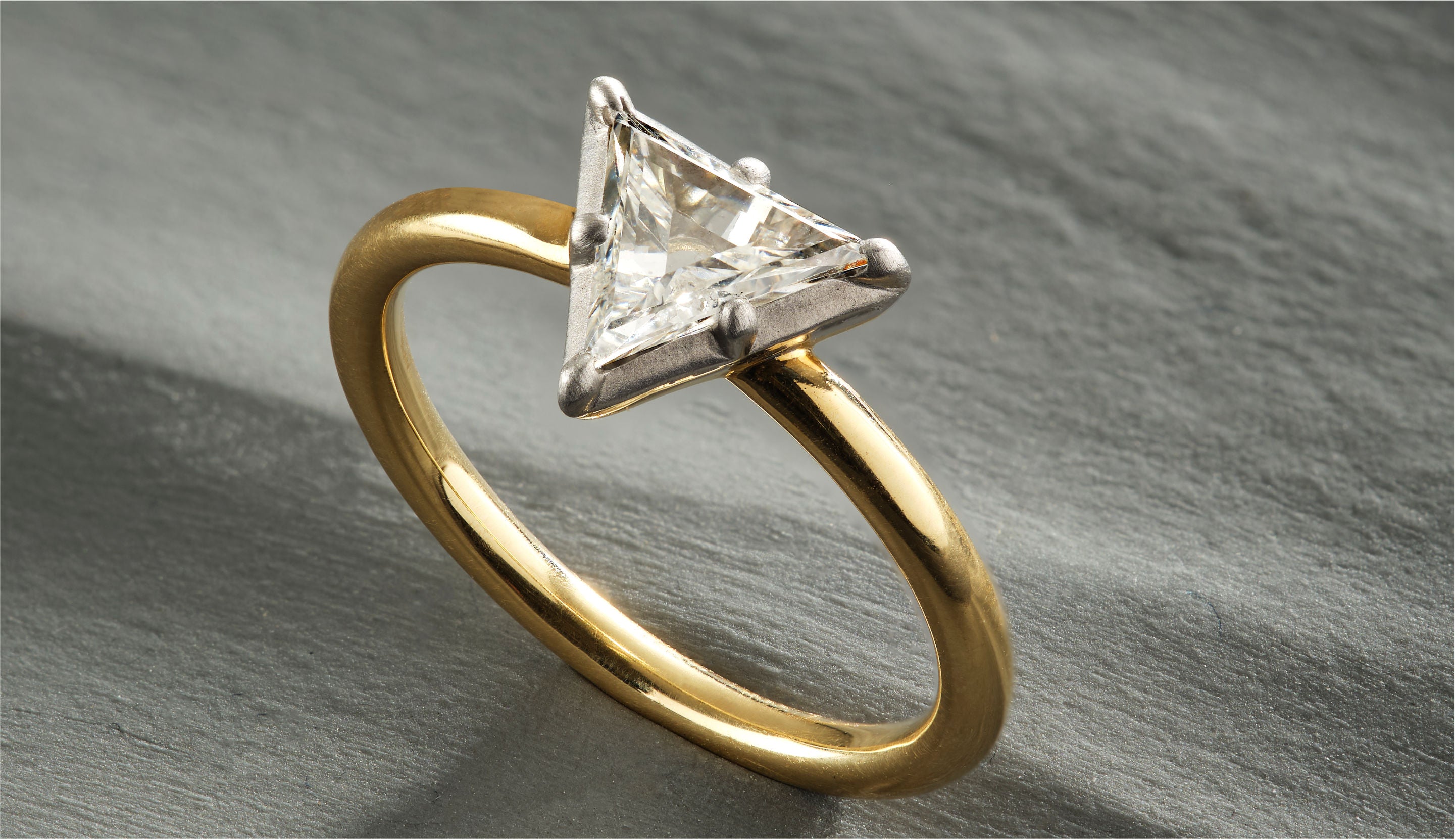 Blonde woman with slicked-back hair wearing a black strapless top and a choker necklace with a large light blue gemstone.