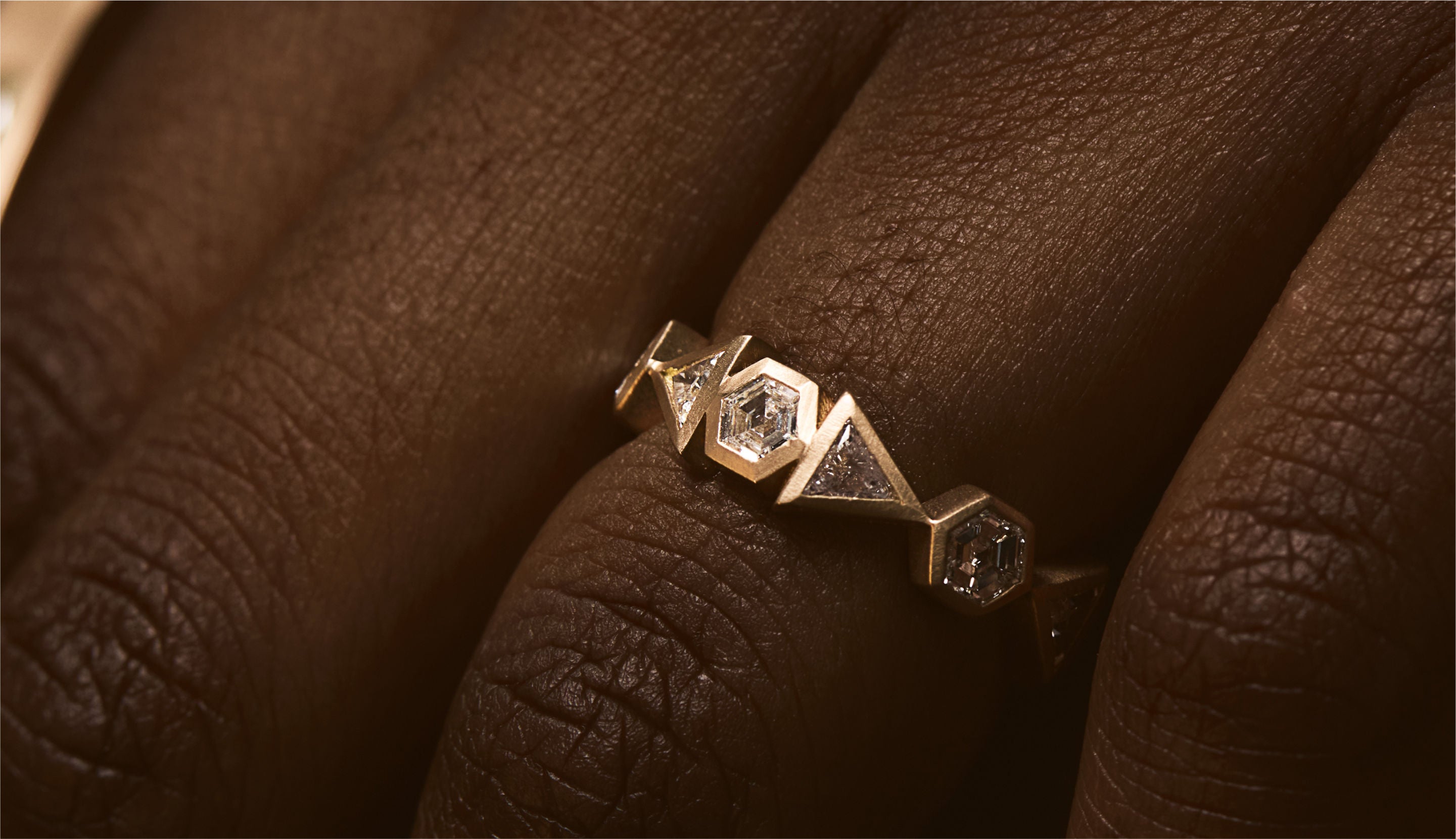 Blonde woman with slicked-back hair wearing a black strapless top and a choker necklace with a large light blue gemstone.