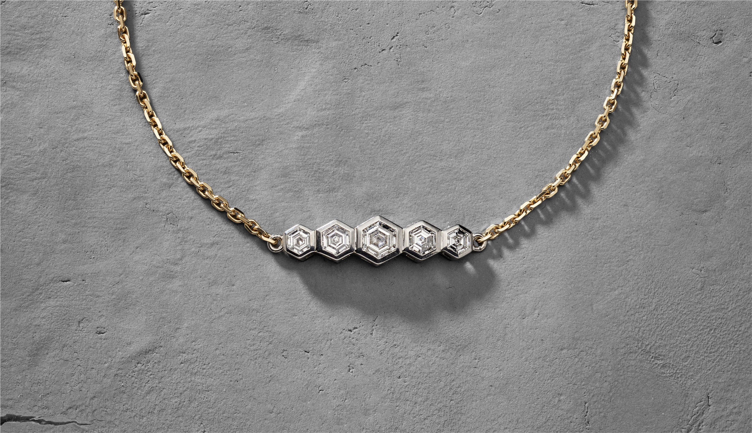 Blonde woman with slicked-back hair wearing a black strapless top and a choker necklace with a large light blue gemstone.