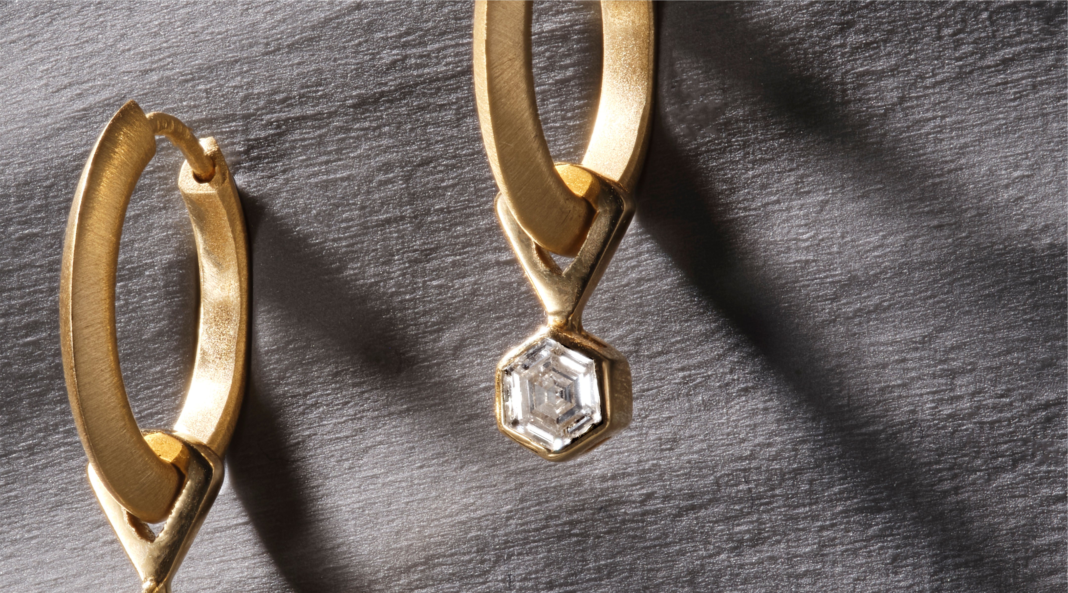 Blonde woman with slicked-back hair wearing a black strapless top and a choker necklace with a large light blue gemstone.