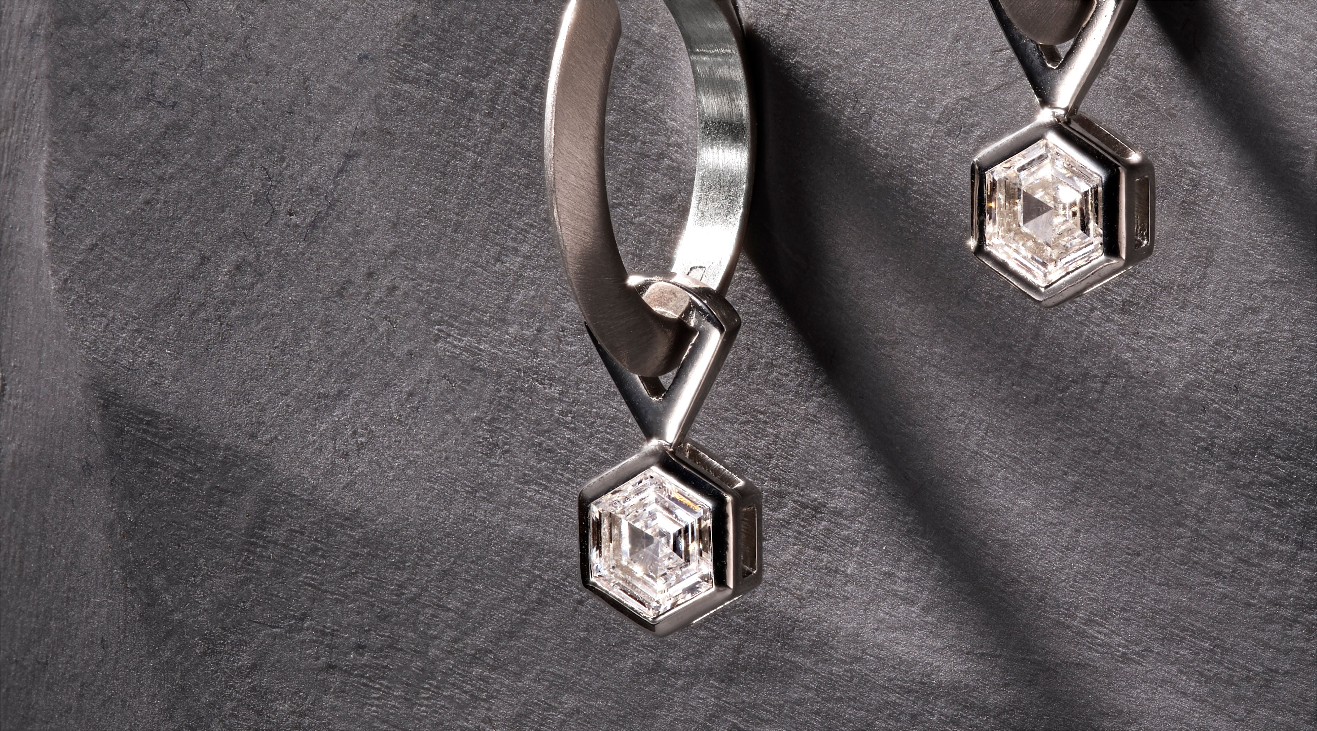 Blonde woman with slicked-back hair wearing a black strapless top and a choker necklace with a large light blue gemstone.