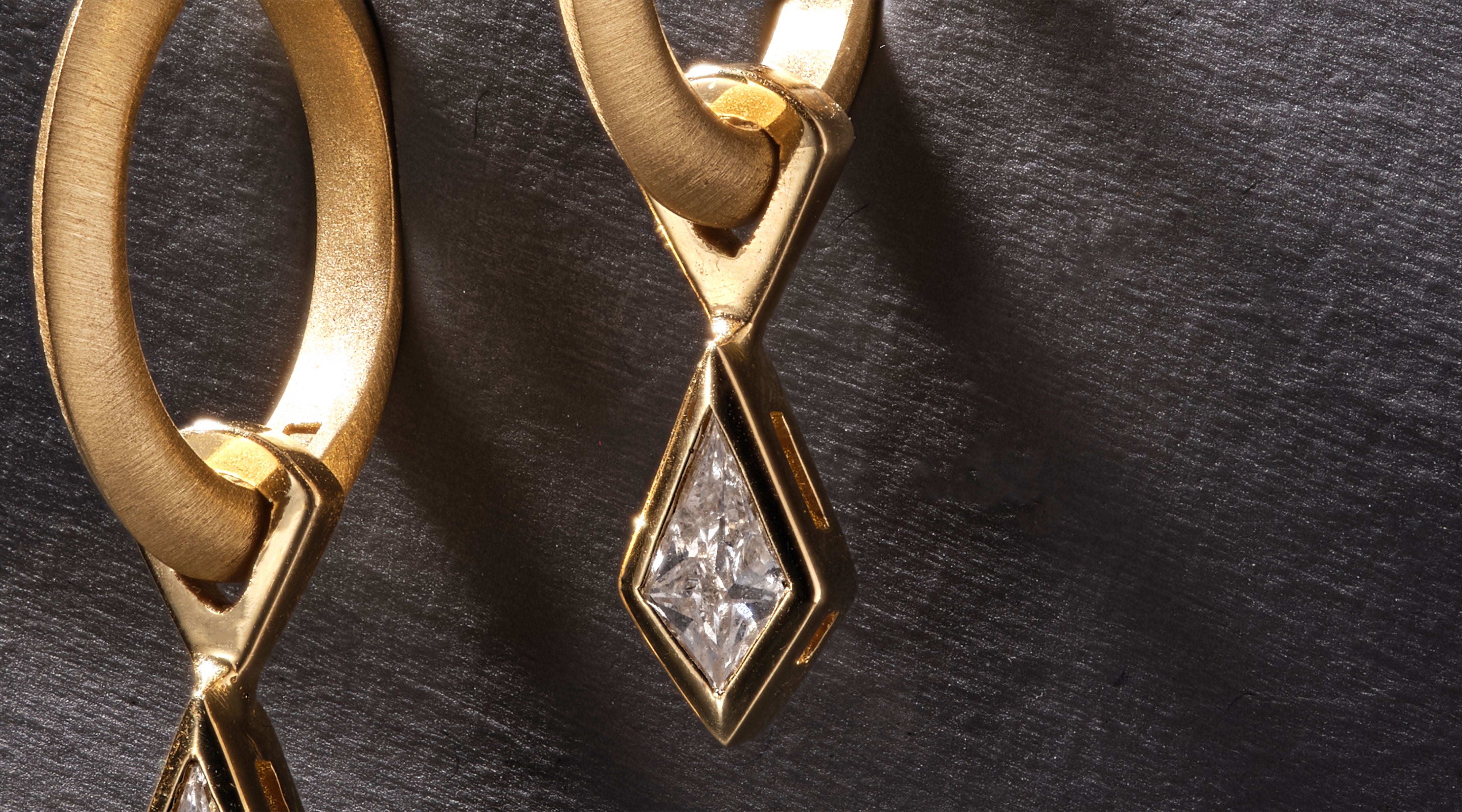 Blonde woman with slicked-back hair wearing a black strapless top and a choker necklace with a large light blue gemstone.