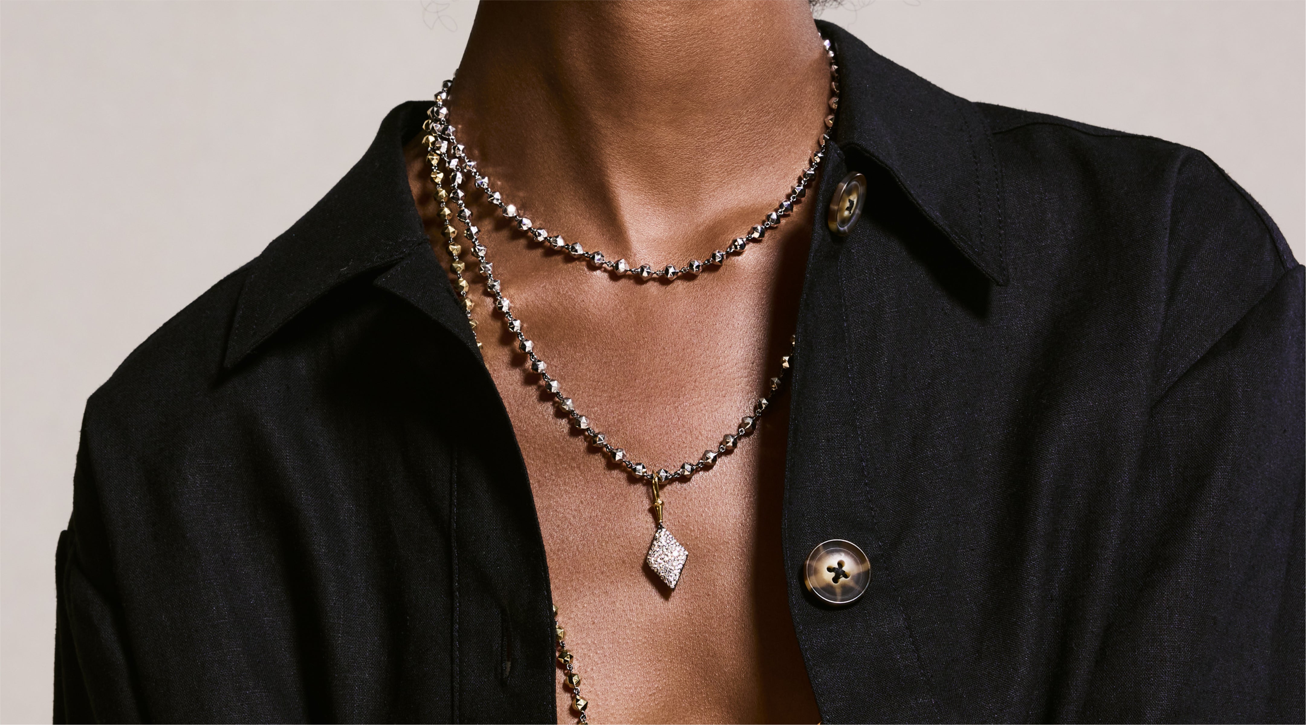 Blonde woman with slicked-back hair wearing a black strapless top and a choker necklace with a large light blue gemstone.