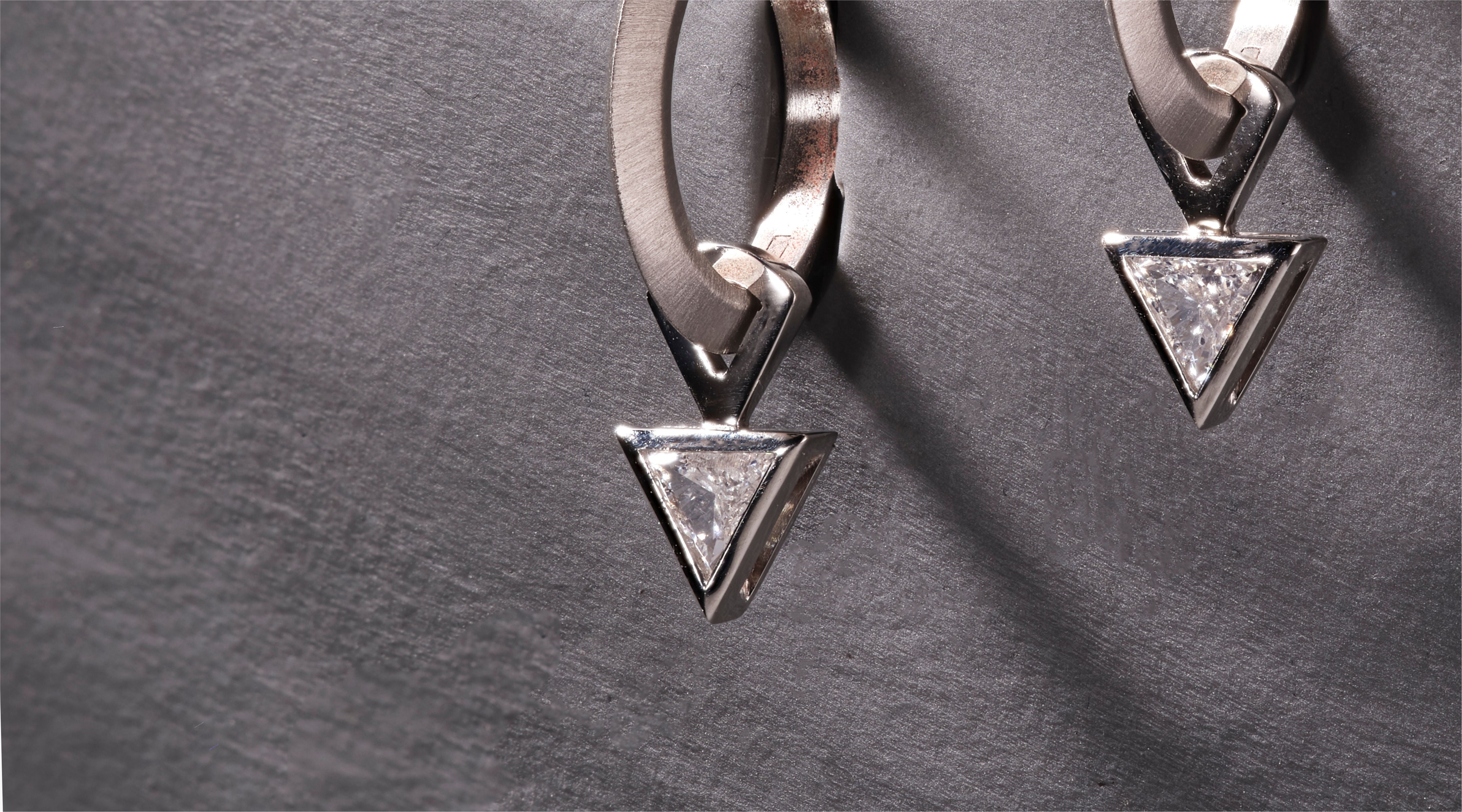 Blonde woman with slicked-back hair wearing a black strapless top and a choker necklace with a large light blue gemstone.