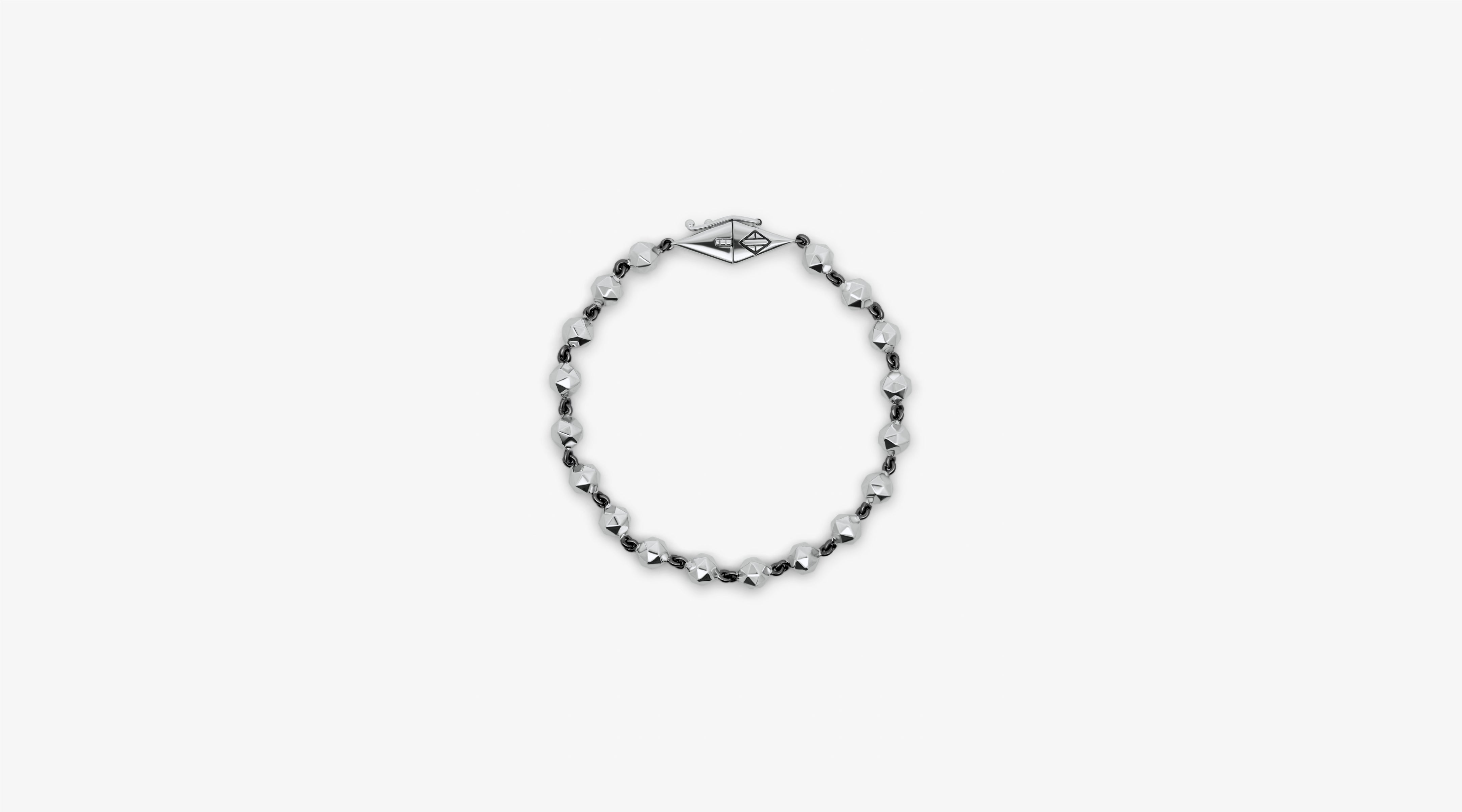 Blonde woman with slicked-back hair wearing a black strapless top and a choker necklace with a large light blue gemstone.