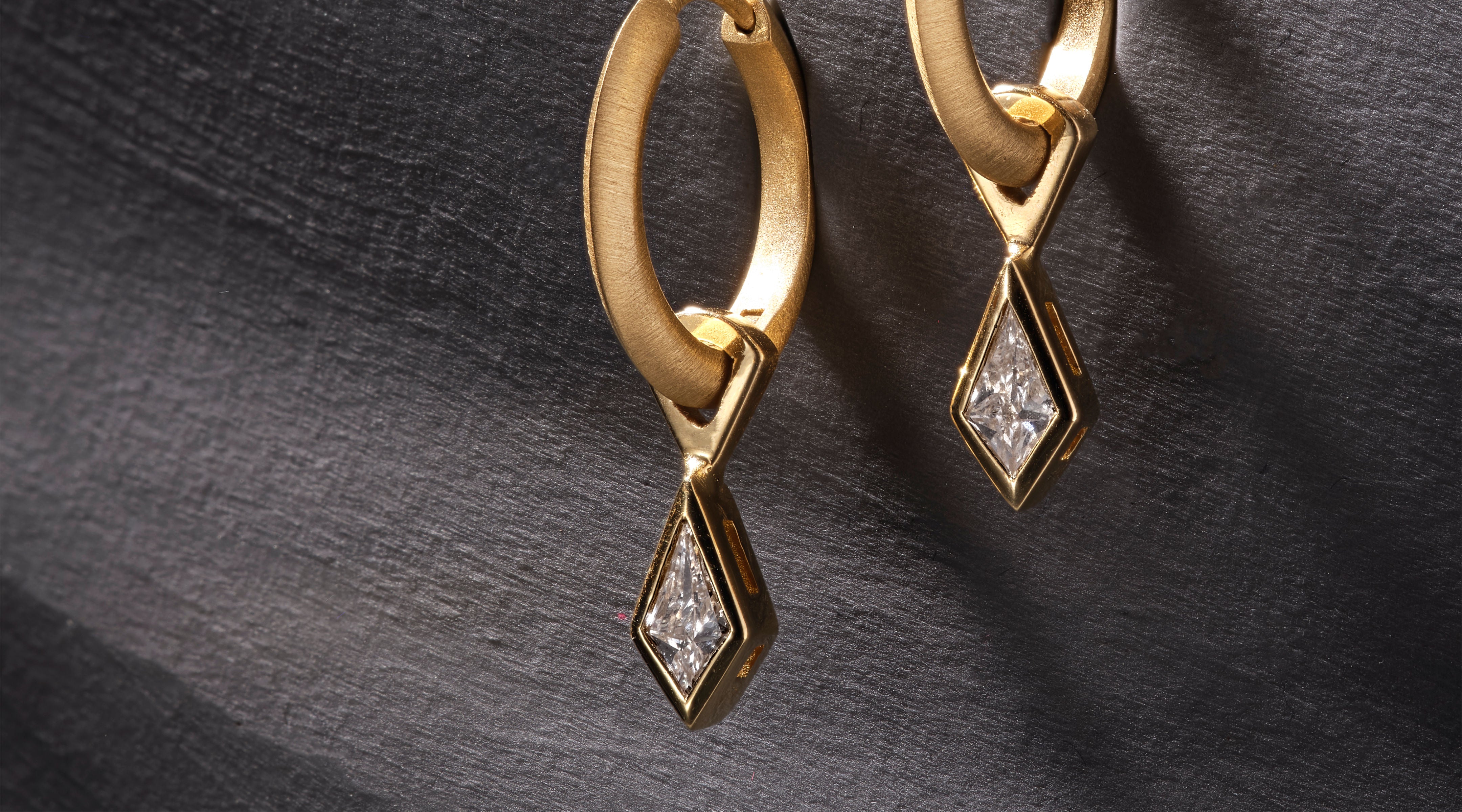 Blonde woman with slicked-back hair wearing a black strapless top and a choker necklace with a large light blue gemstone.