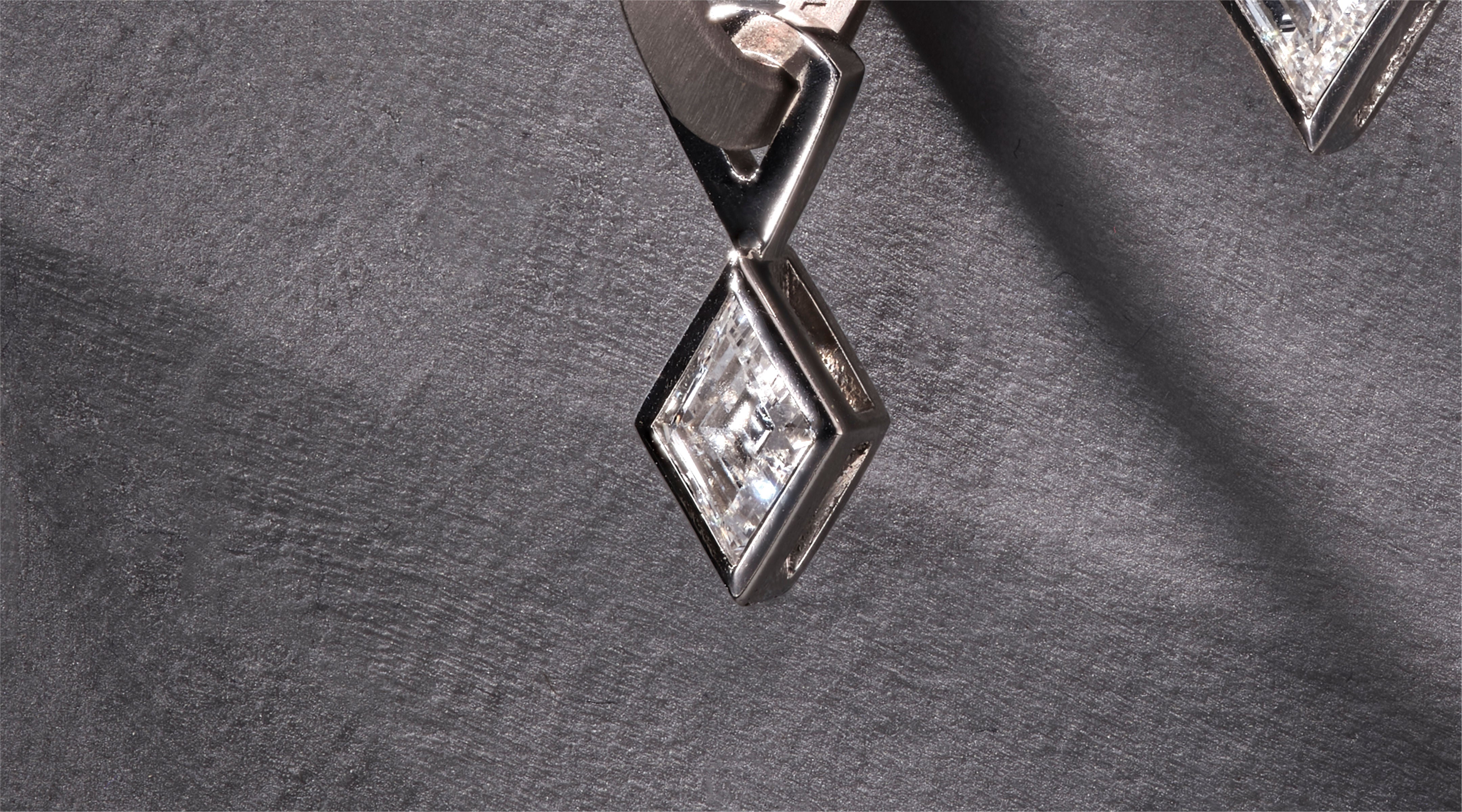 Blonde woman with slicked-back hair wearing a black strapless top and a choker necklace with a large light blue gemstone.