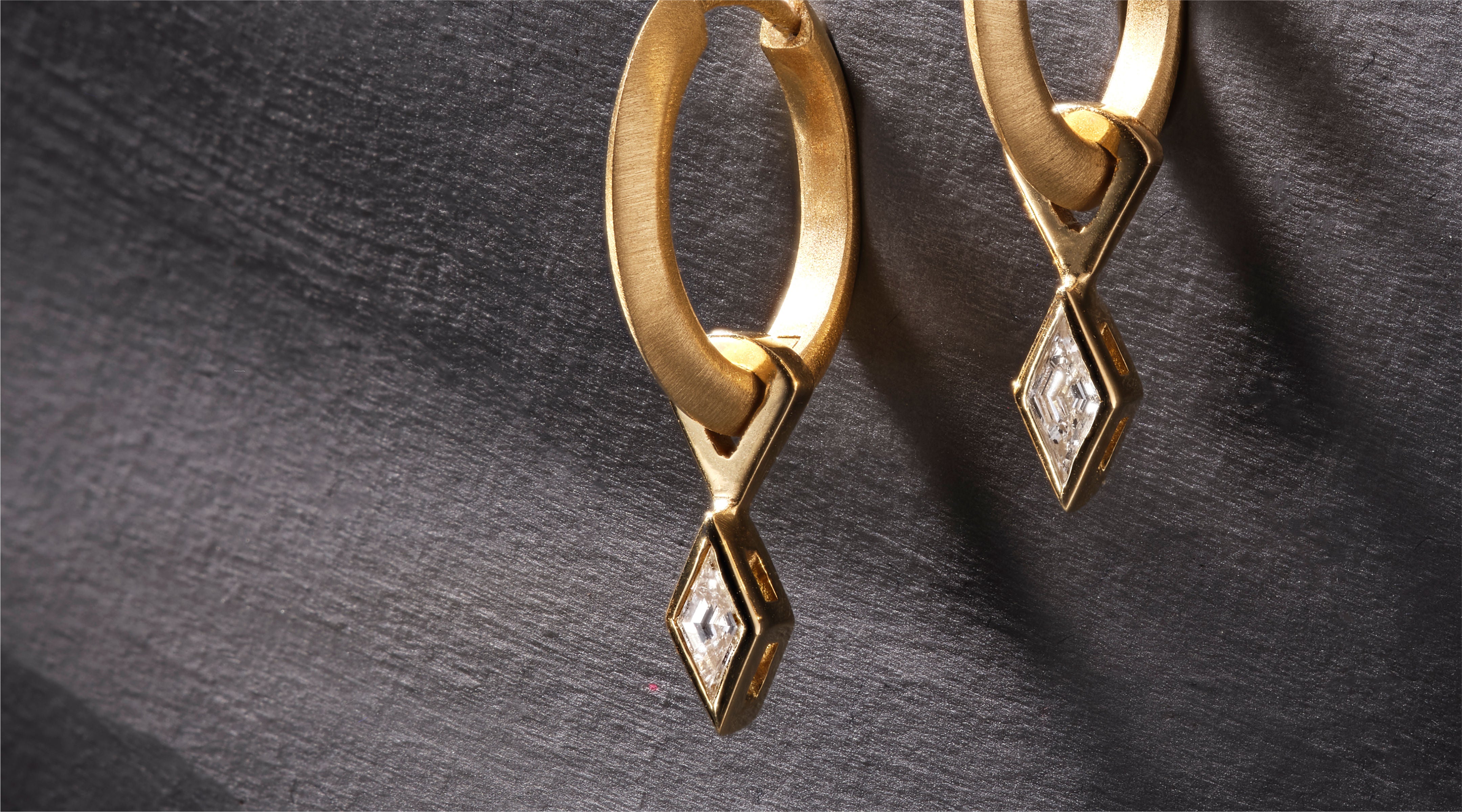 Blonde woman with slicked-back hair wearing a black strapless top and a choker necklace with a large light blue gemstone.