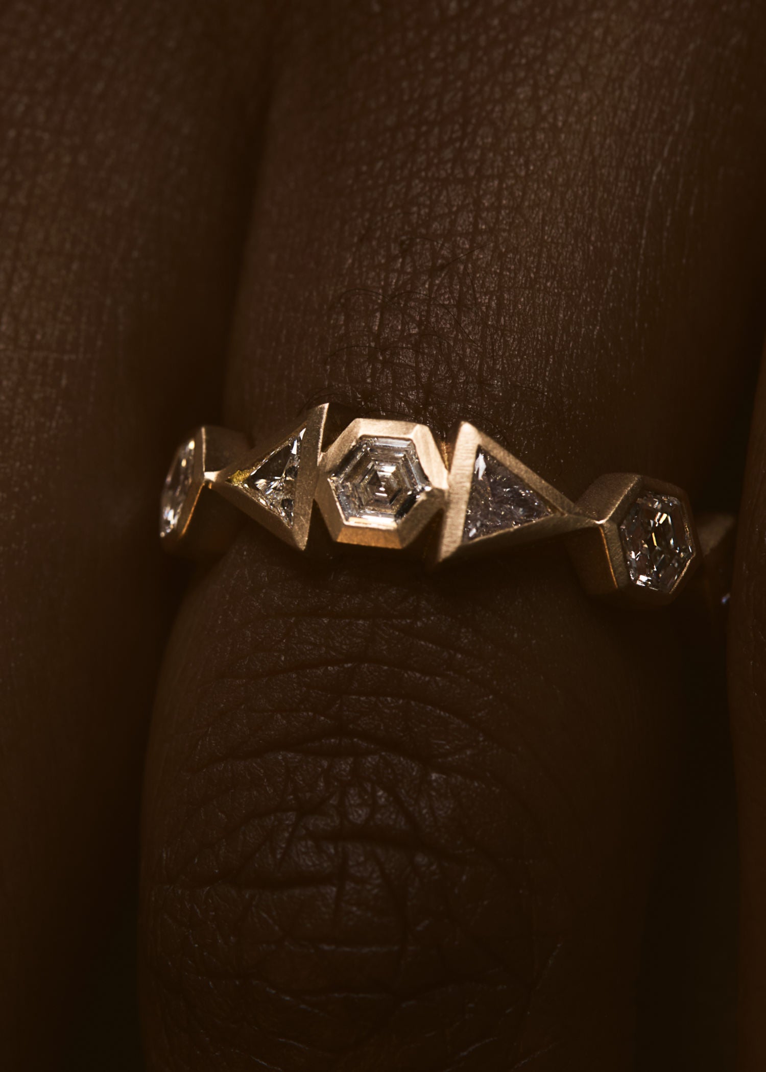 Gold ring with diamond accents on a light gray background.