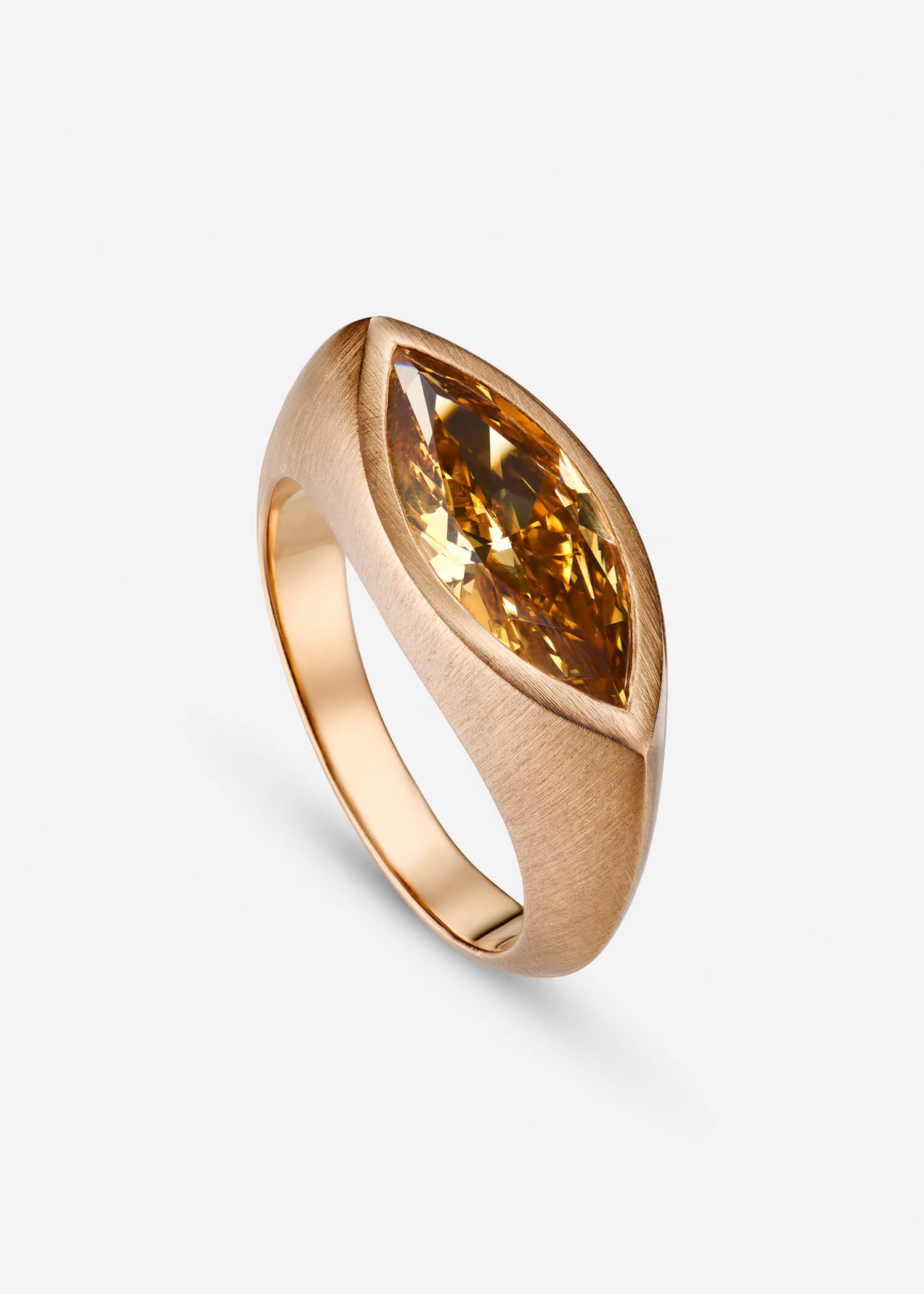 Rose gold ring with a amber stone on a textured beige surface.
