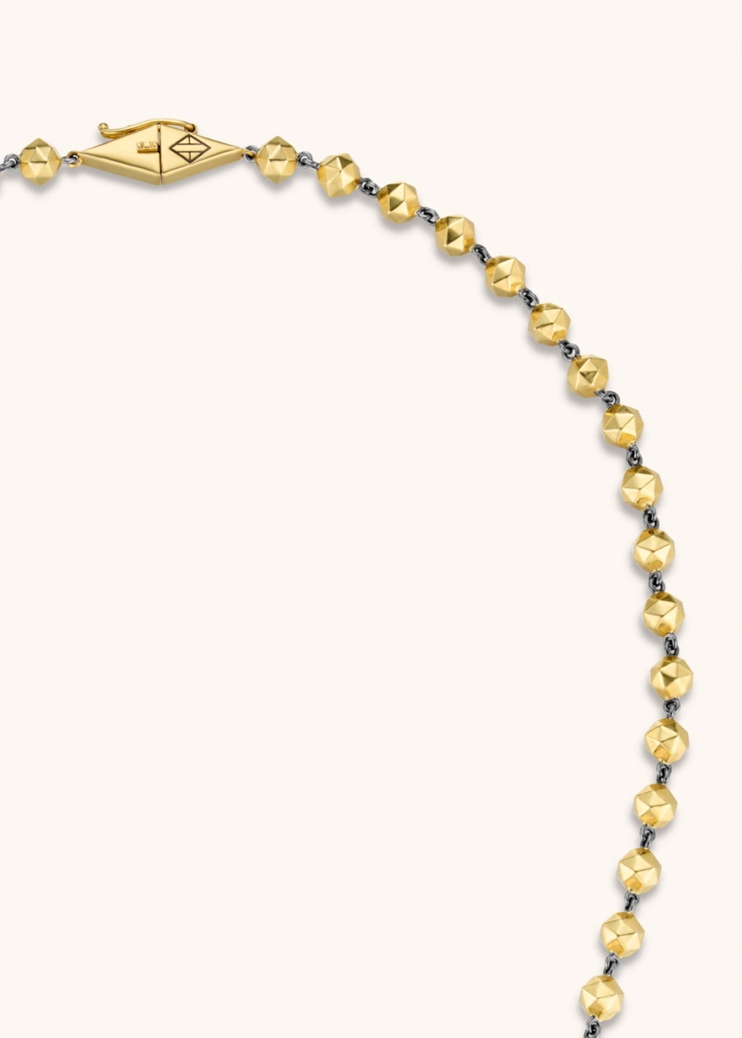 Person wearing a black shirt with a necklace against a neutral background.