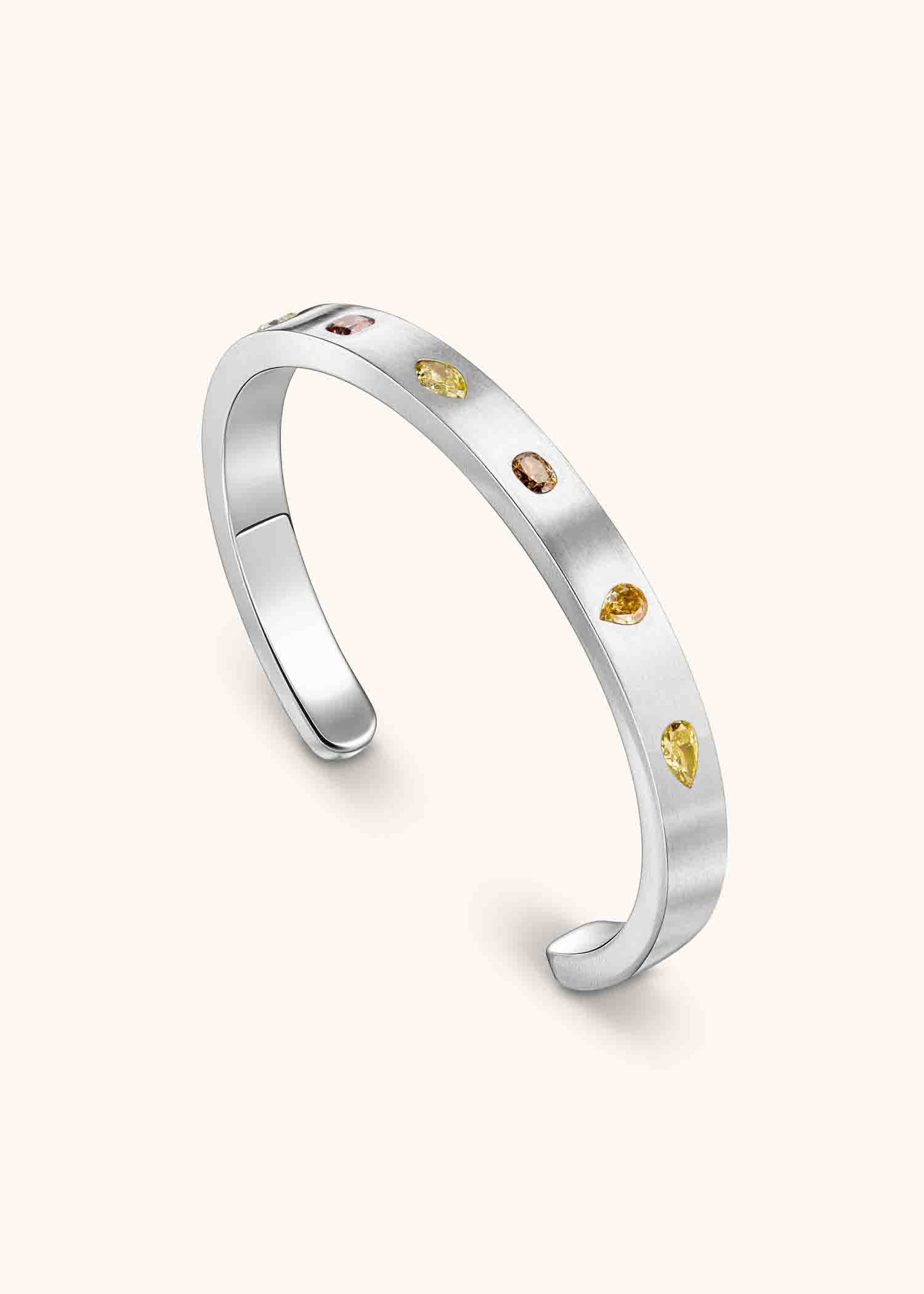 Platinum cuff bracelet with mixed fancy-cut diamonds on matte textured surface.