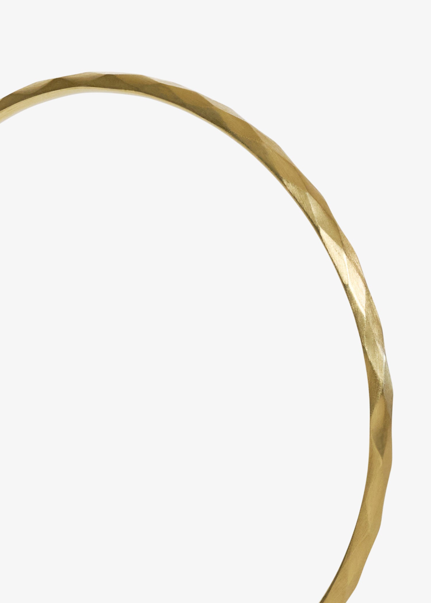Close up detail of gold bangle on a white background.