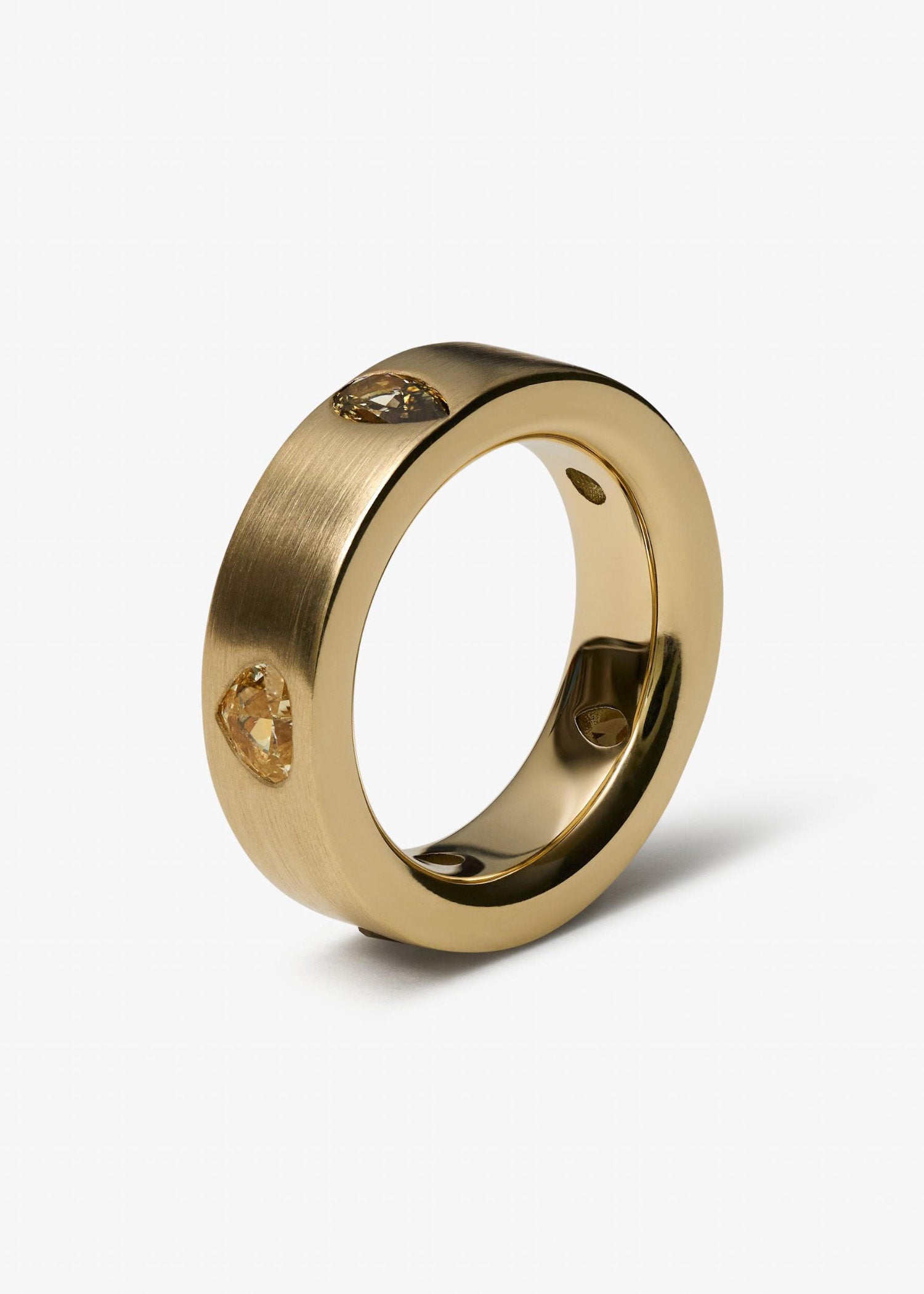 Yellow gold diamond ring with pear and round stones displayed on grey textured background.