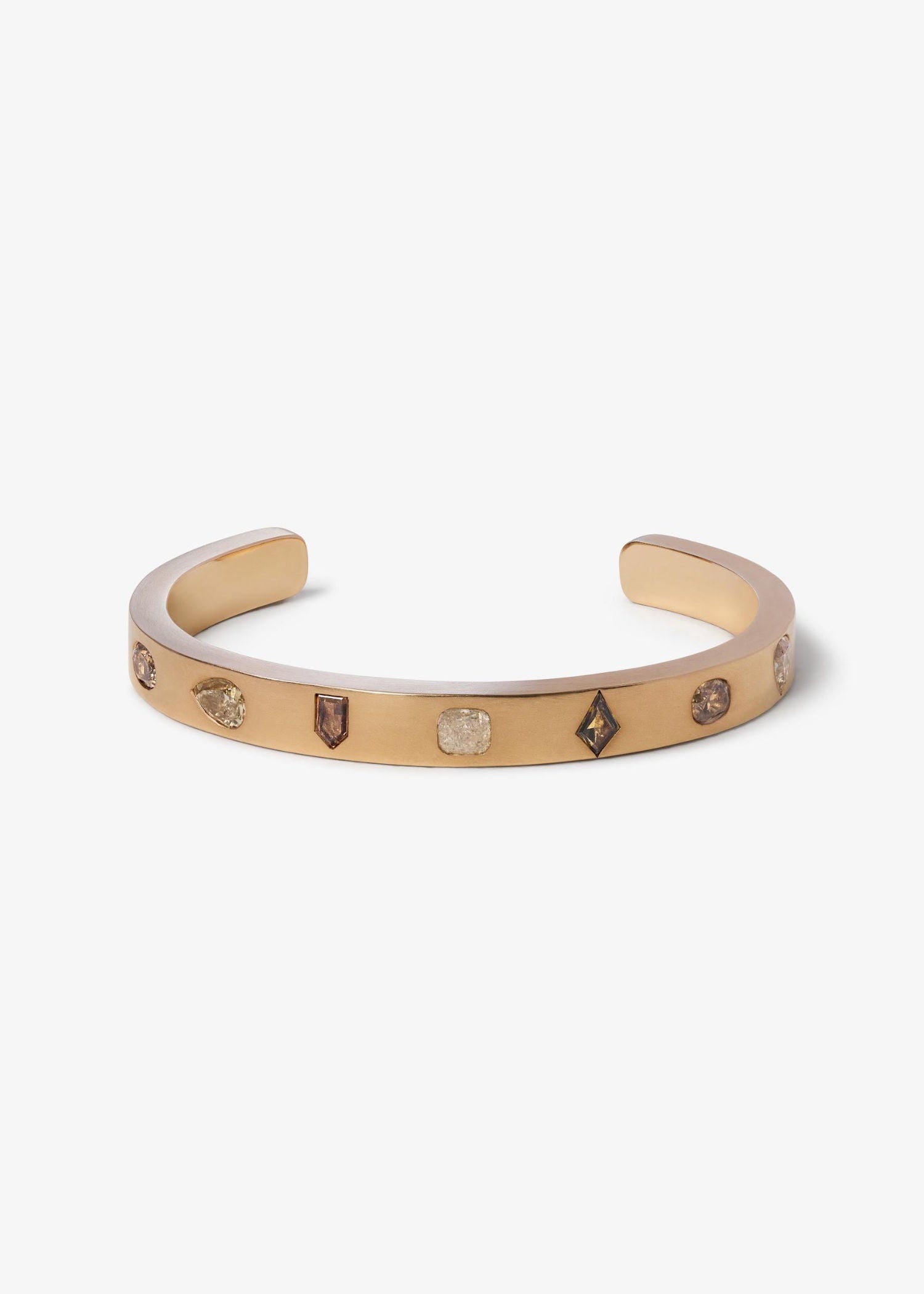 Rose gold bracelet with engraved letters on a gray fabric background.
