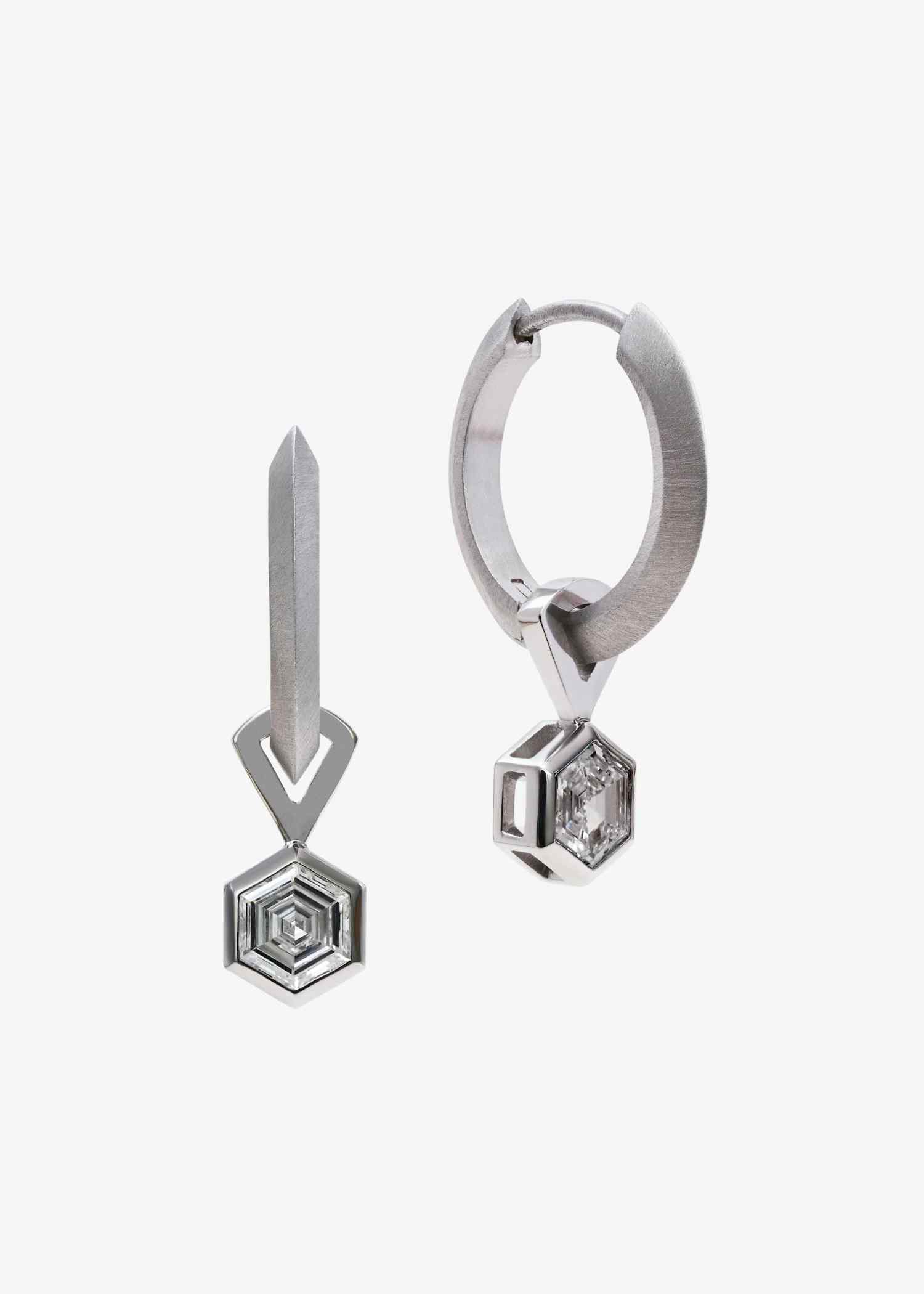 Platinum hoop earrings featuring hexagon-cut diamonds on grey textured surface.