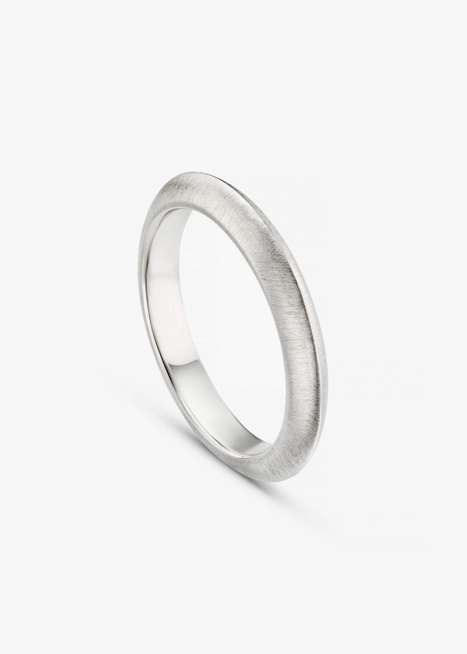 Simple white gold knife-edge ring on a textured gray surface.