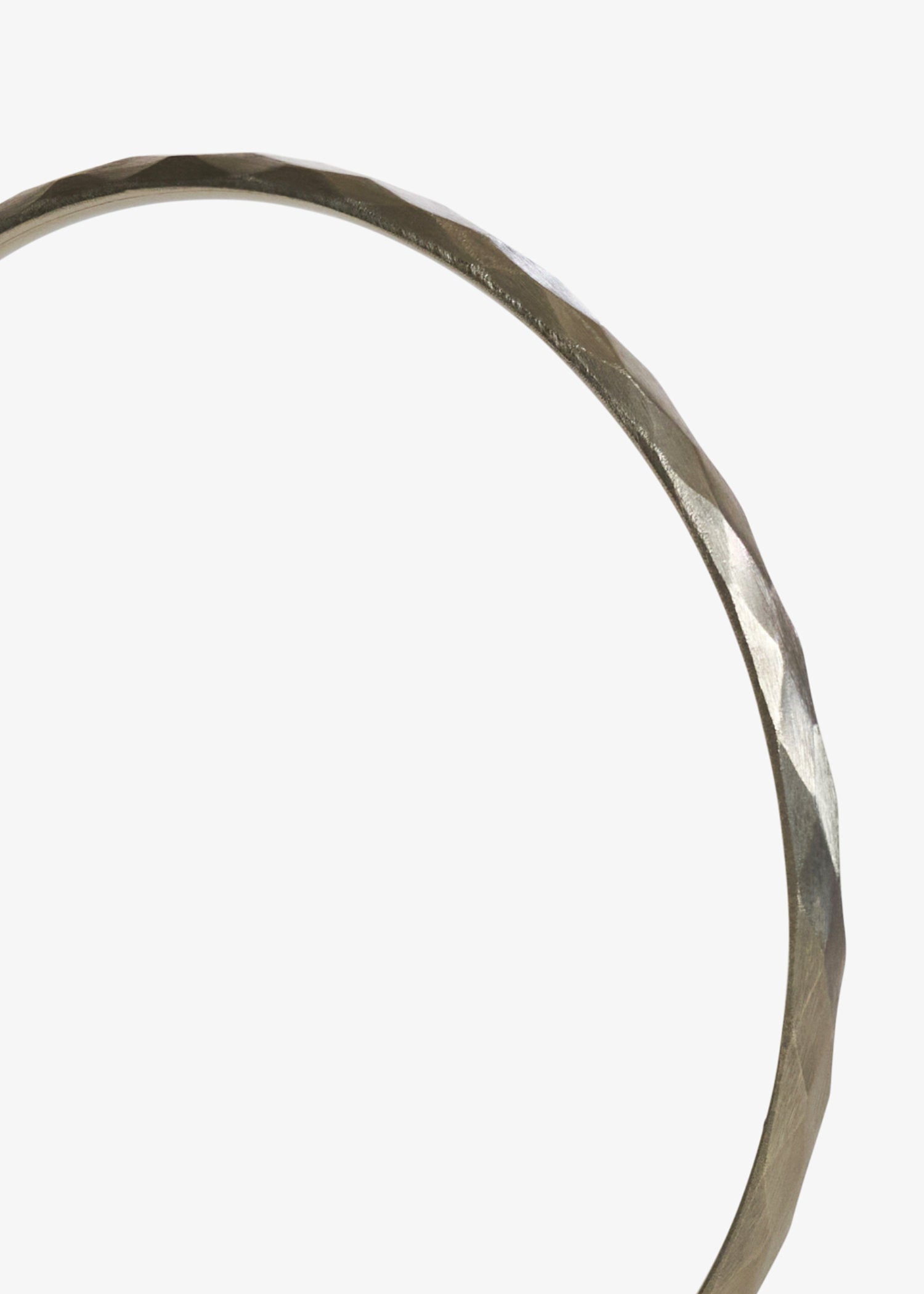 Close up detail of white gold facet bangle in white background.