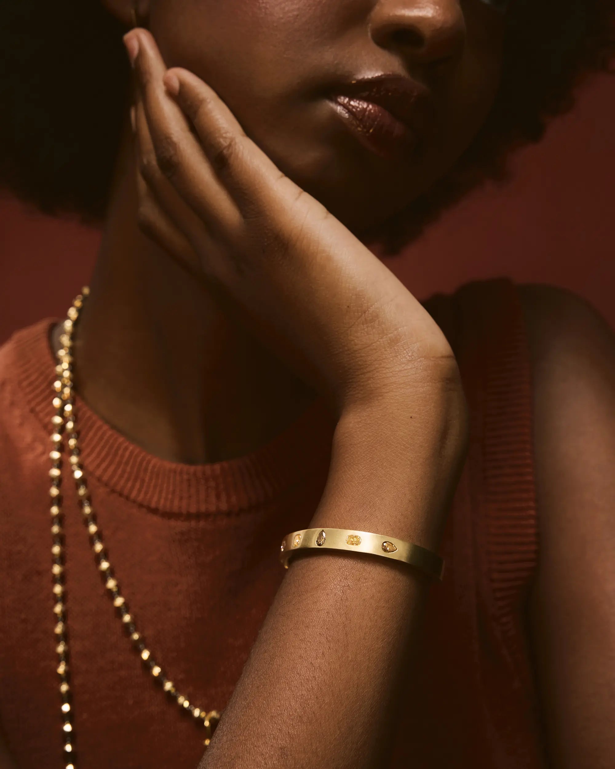 Close-up of a person wearing a gold bracelet with a blurred background.