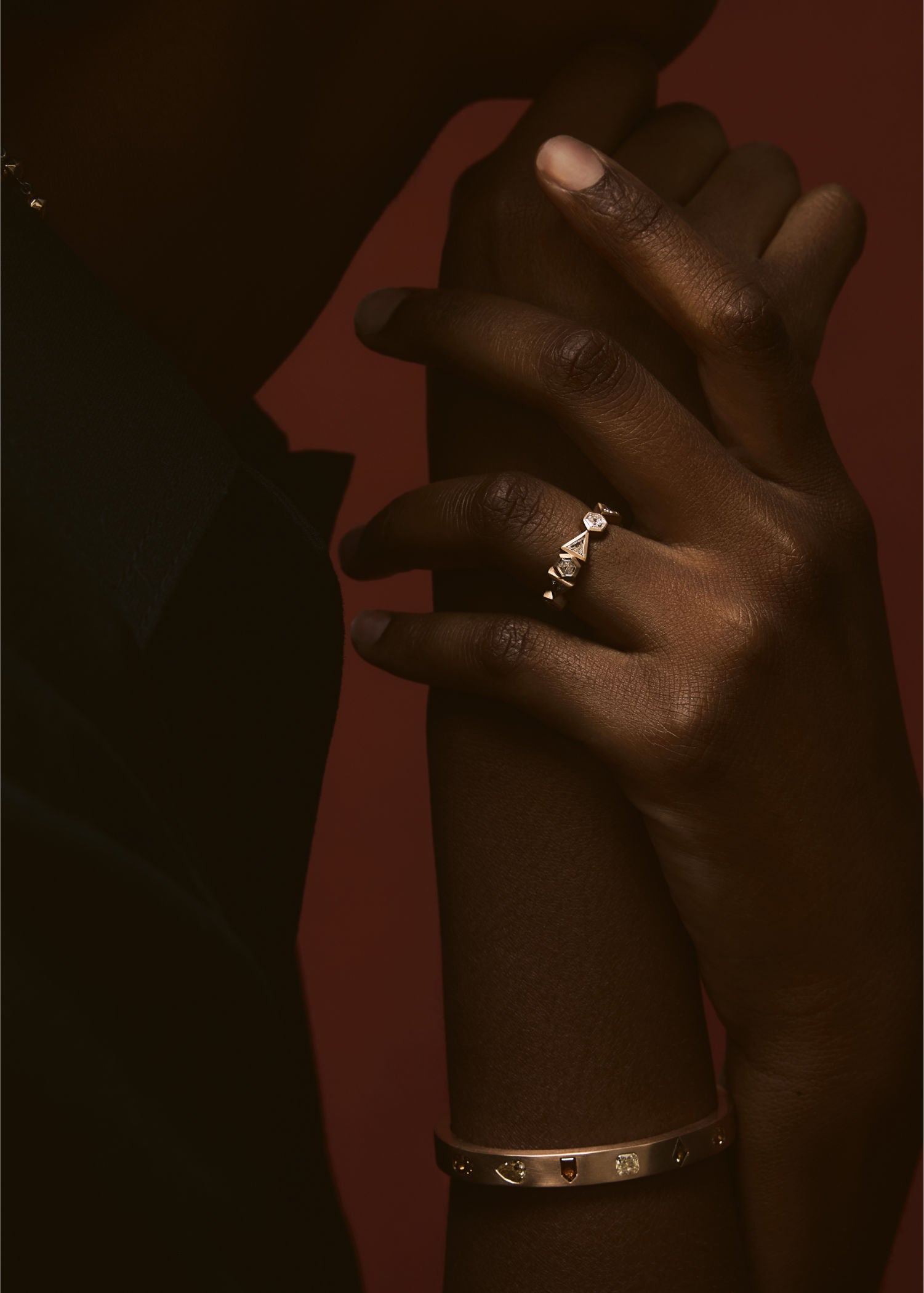 Model wearing gold diamond crown ring with geometric design on finger.