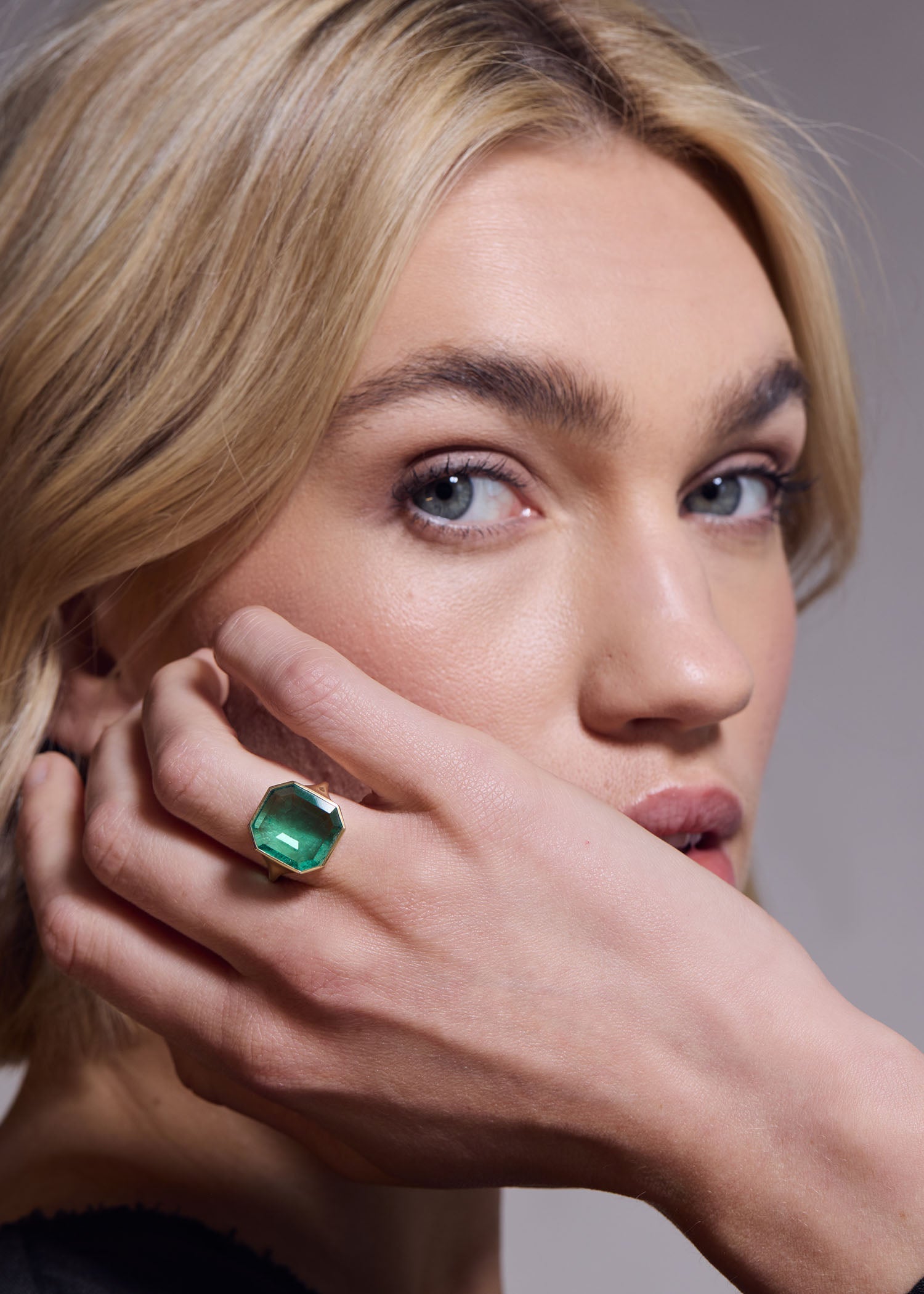 Woman wearing a green gemstone ring on her finger.