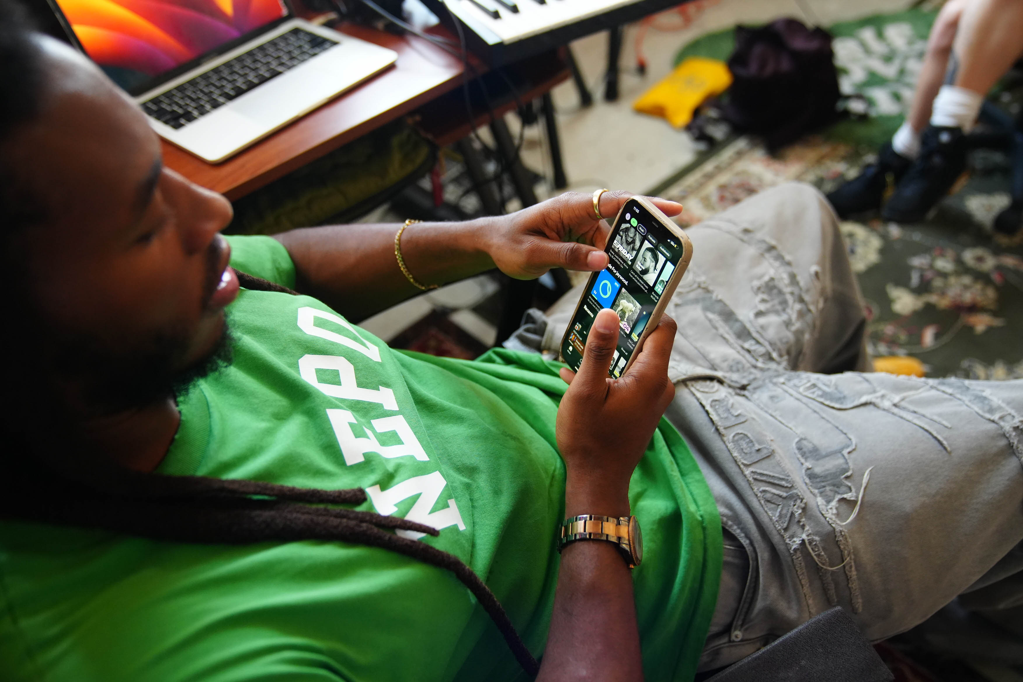 A young man looks down at his phone, scrolling through applications.