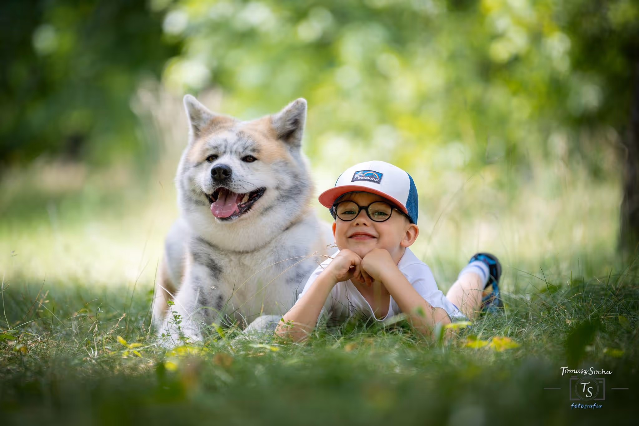 dziecko leżące na trawie obok psa, podczas terapii