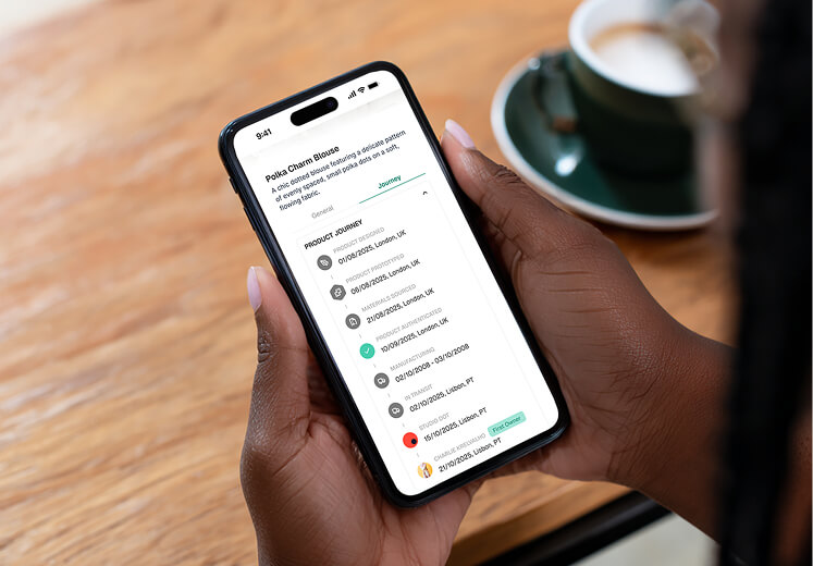 Person holding a smartphone displaying a product journey timeline for a Polka Charm Blouse with detailed dates and locations.